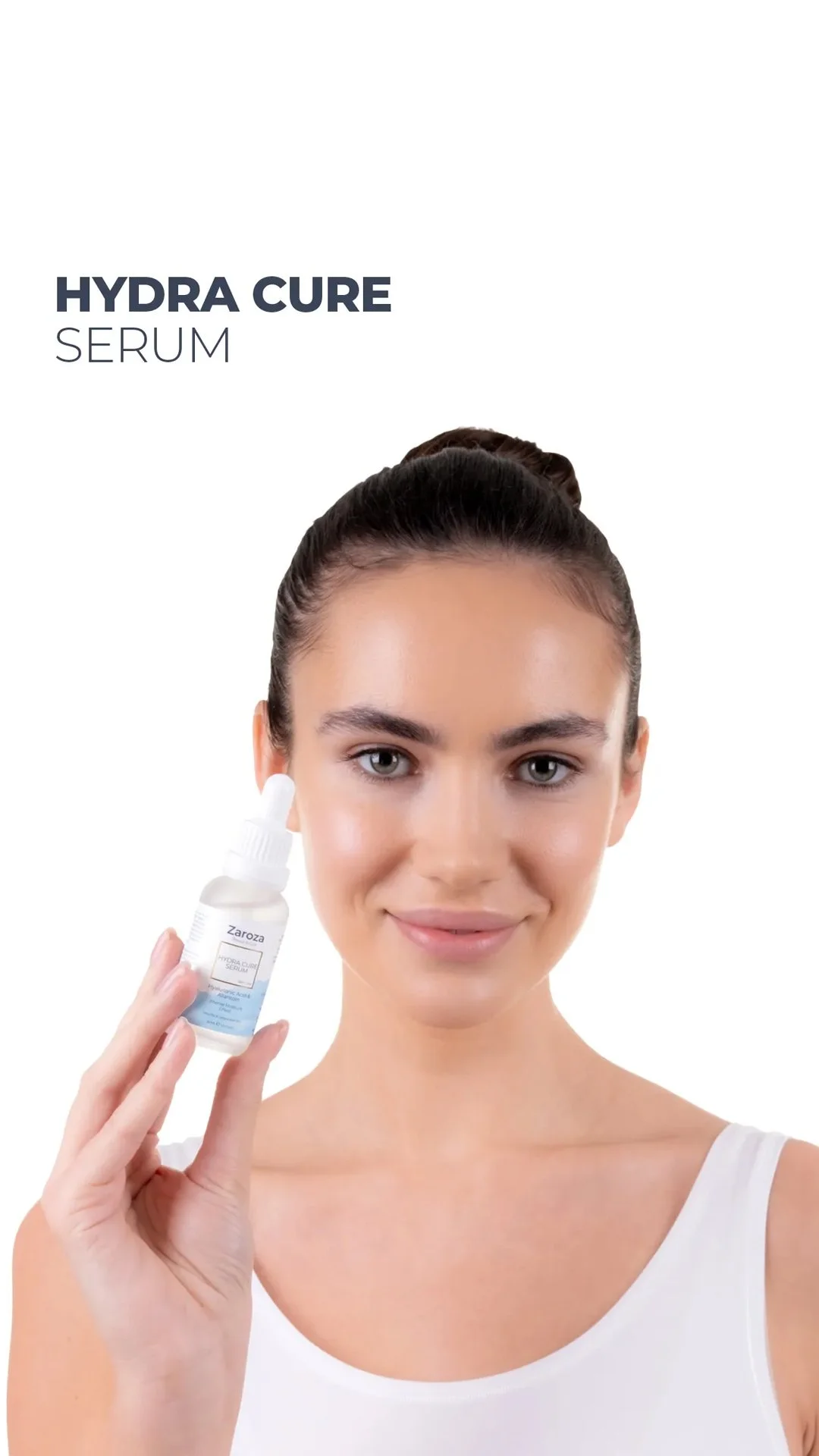 Woman smiling holding a bottle of Hydra Cure Serum against a white background.