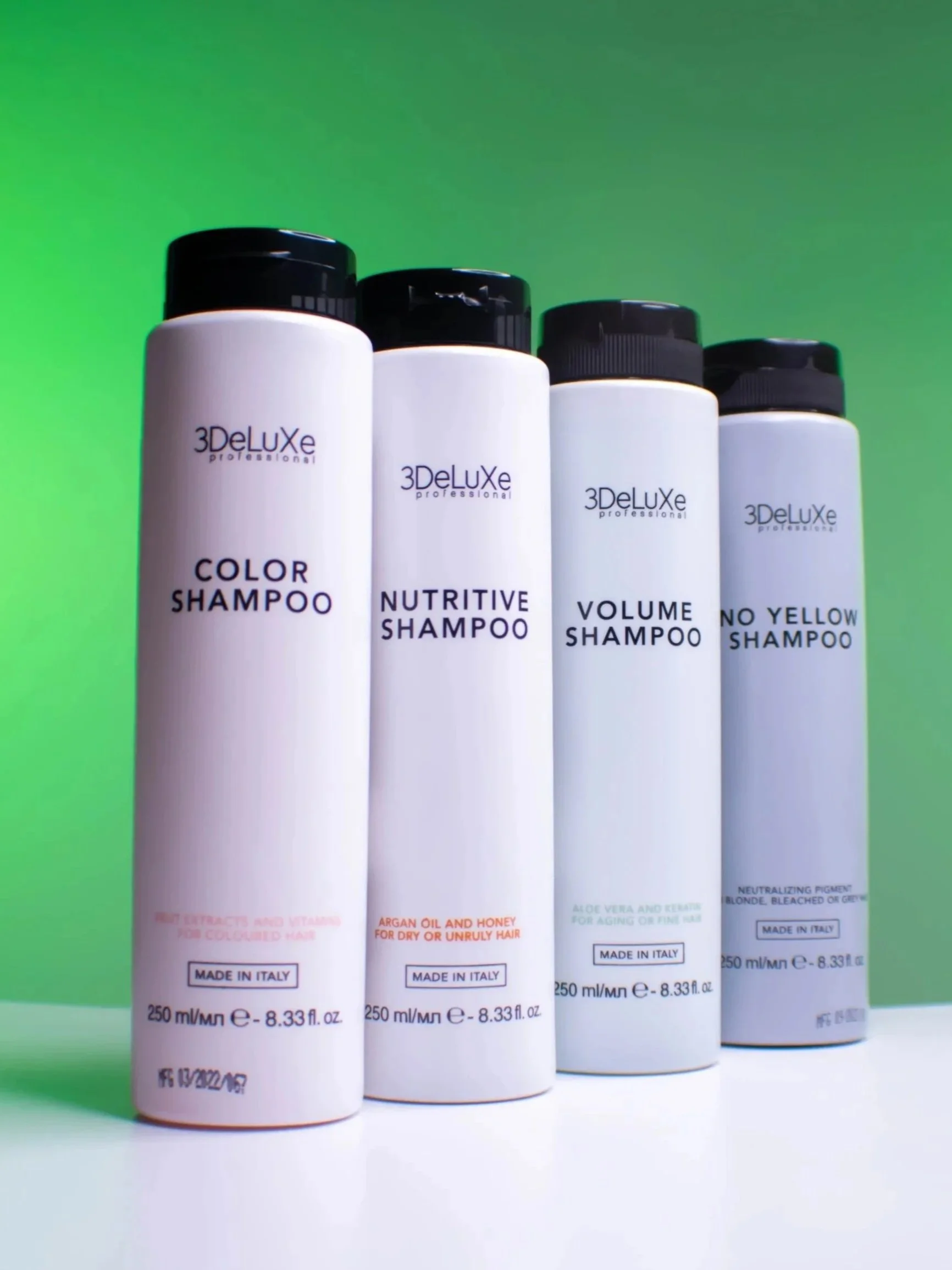 Four bottles of 3DeLuxe professional shampoo lined up against a green background, labeled as color shampoo, nutritive shampoo, volume shampoo, and no yellow shampoo, each containing 250 ml.