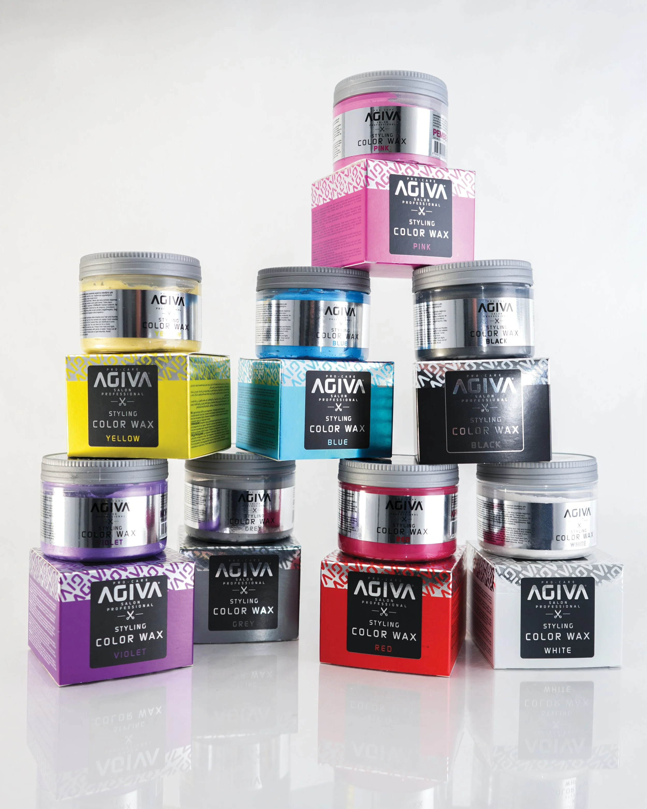 Stacked containers of Agiva styling color wax in various colors including yellow, blue, black, purple, grey, red, and white, with matching boxes.