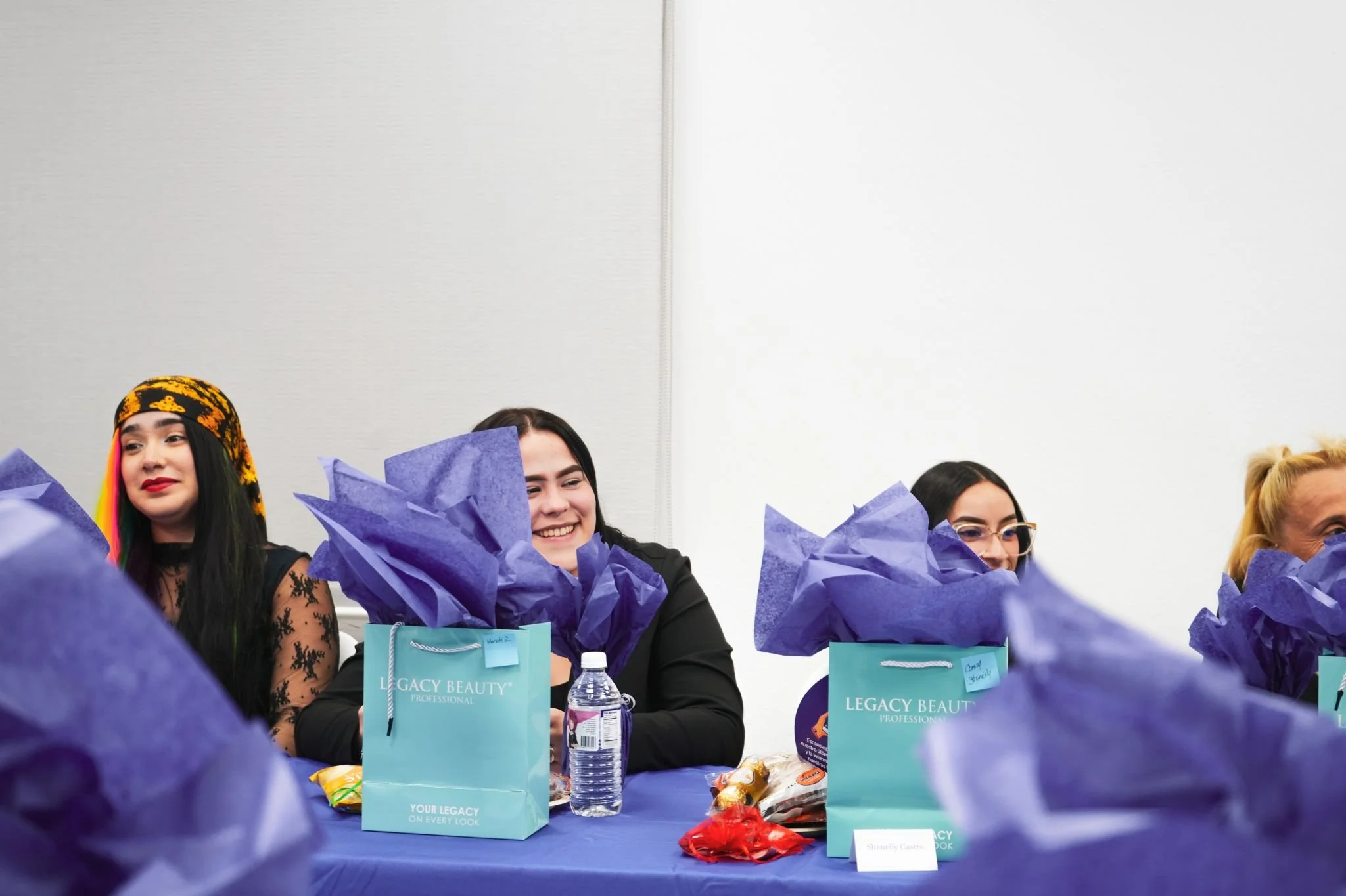 People sitting at a table with purple gift bags and decorations during an event