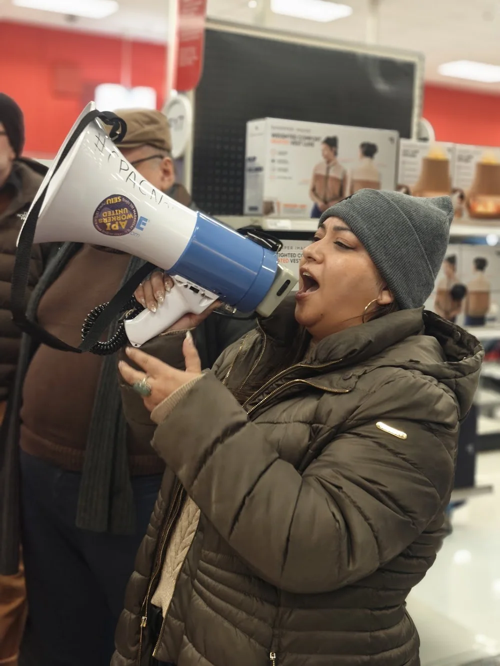 Patty García speaking through a megaphone at a community action