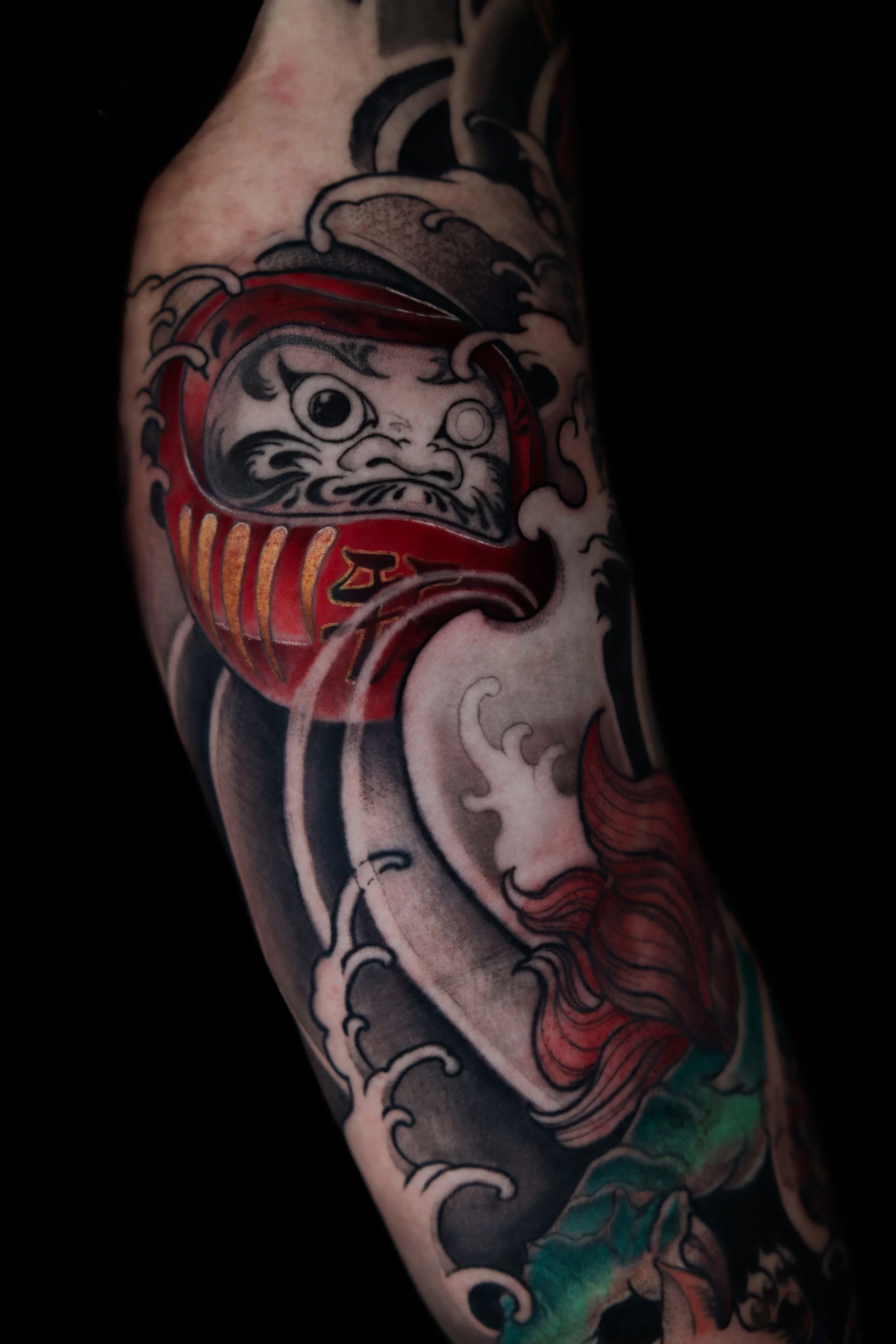 Tattoo of a traditional Japanese-style fish and wave design.