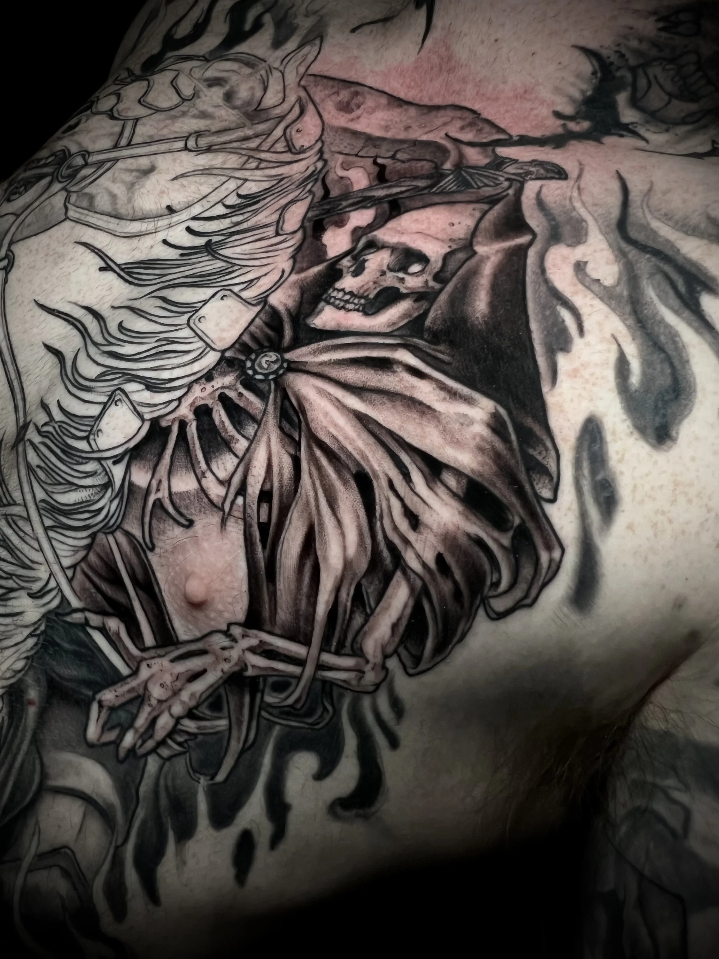 A tattoo featuring a skull within a butterfly, with flames surrounding it, on a person's skin.