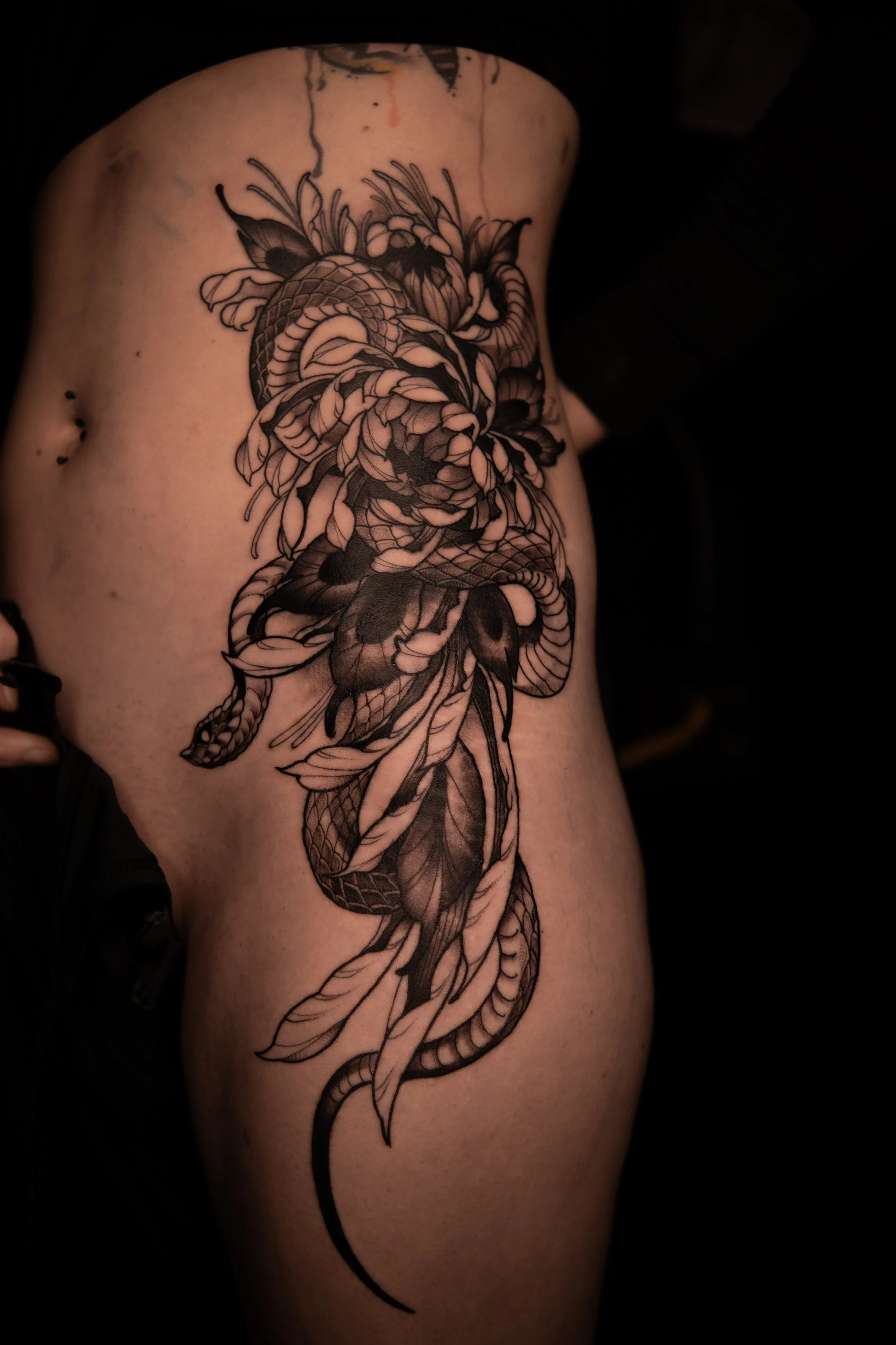 Black and grey tattoo of a dragon on a person's side.