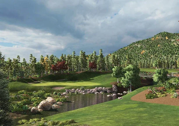 A scenic golf course with a pond, surrounded by trees and a hilly landscape under a partly cloudy sky.