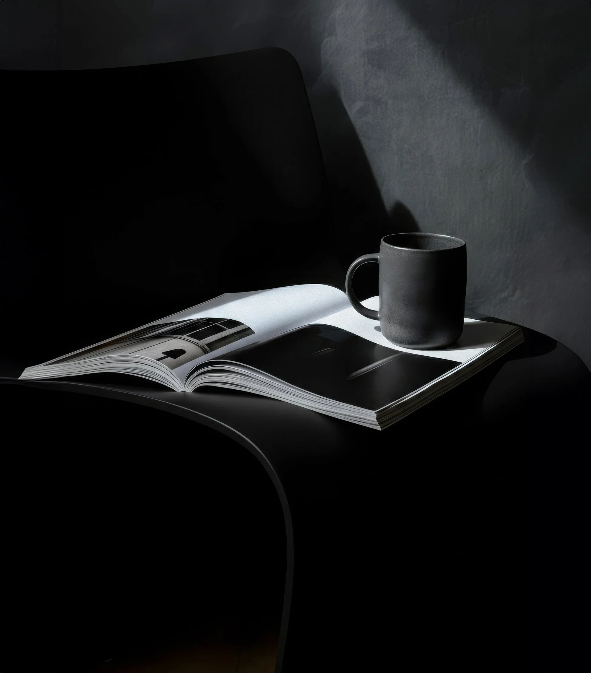 A desk with an open magazine and a dark mug on top, with a shadowy background and dramatic lighting.