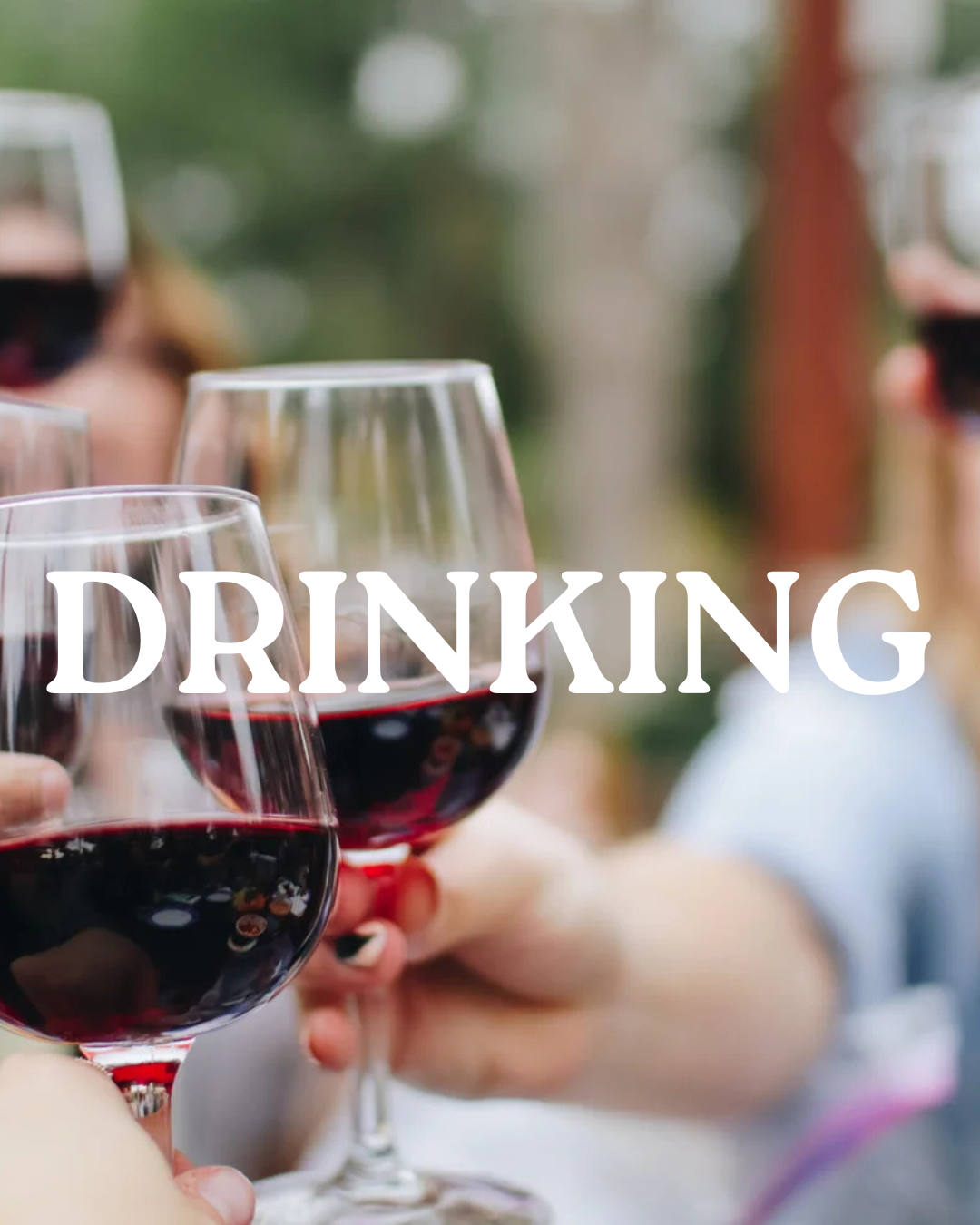 A group of hands cheersing red wine glasses.