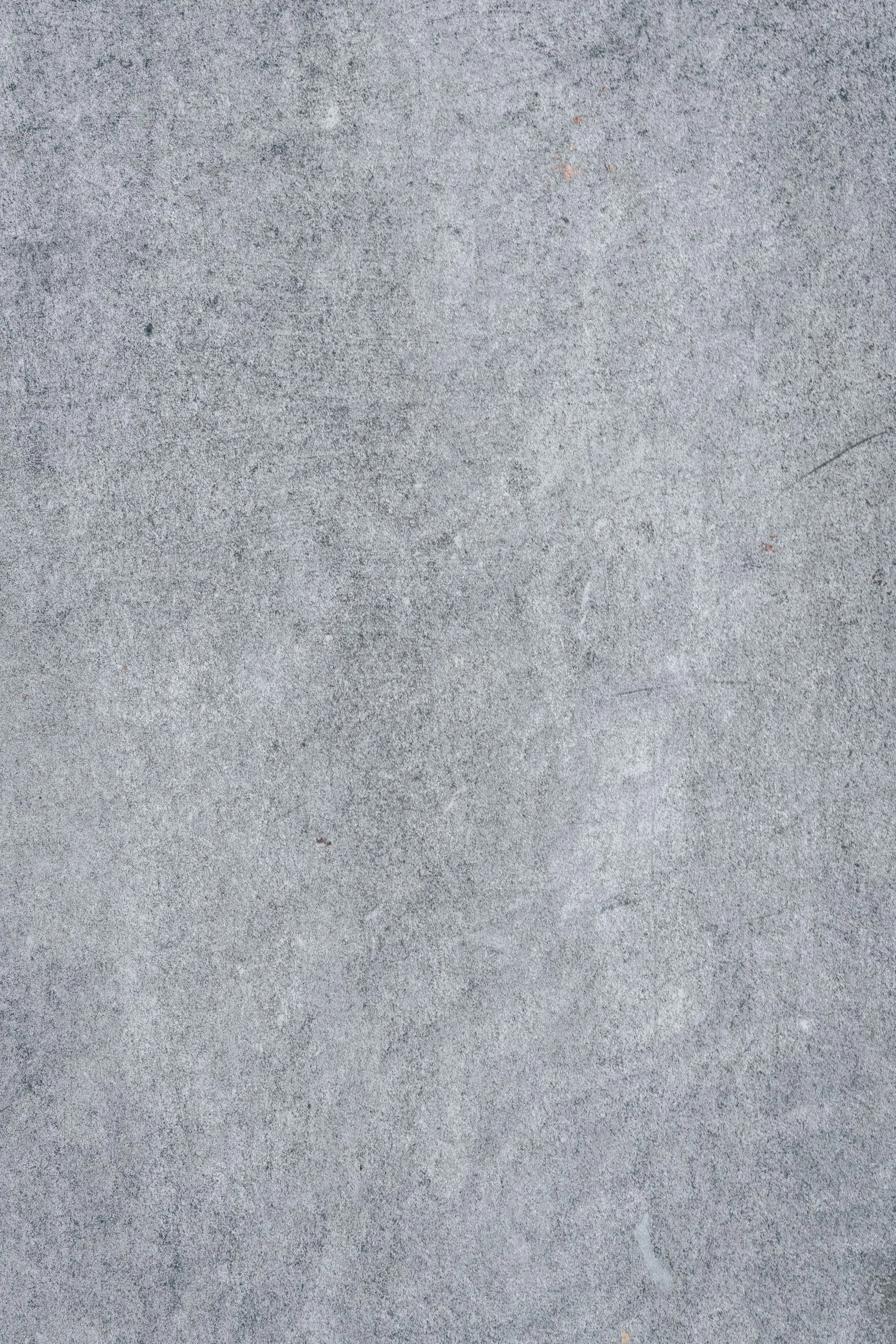 Close-up of a concrete surface with small cracks and scattered dust.