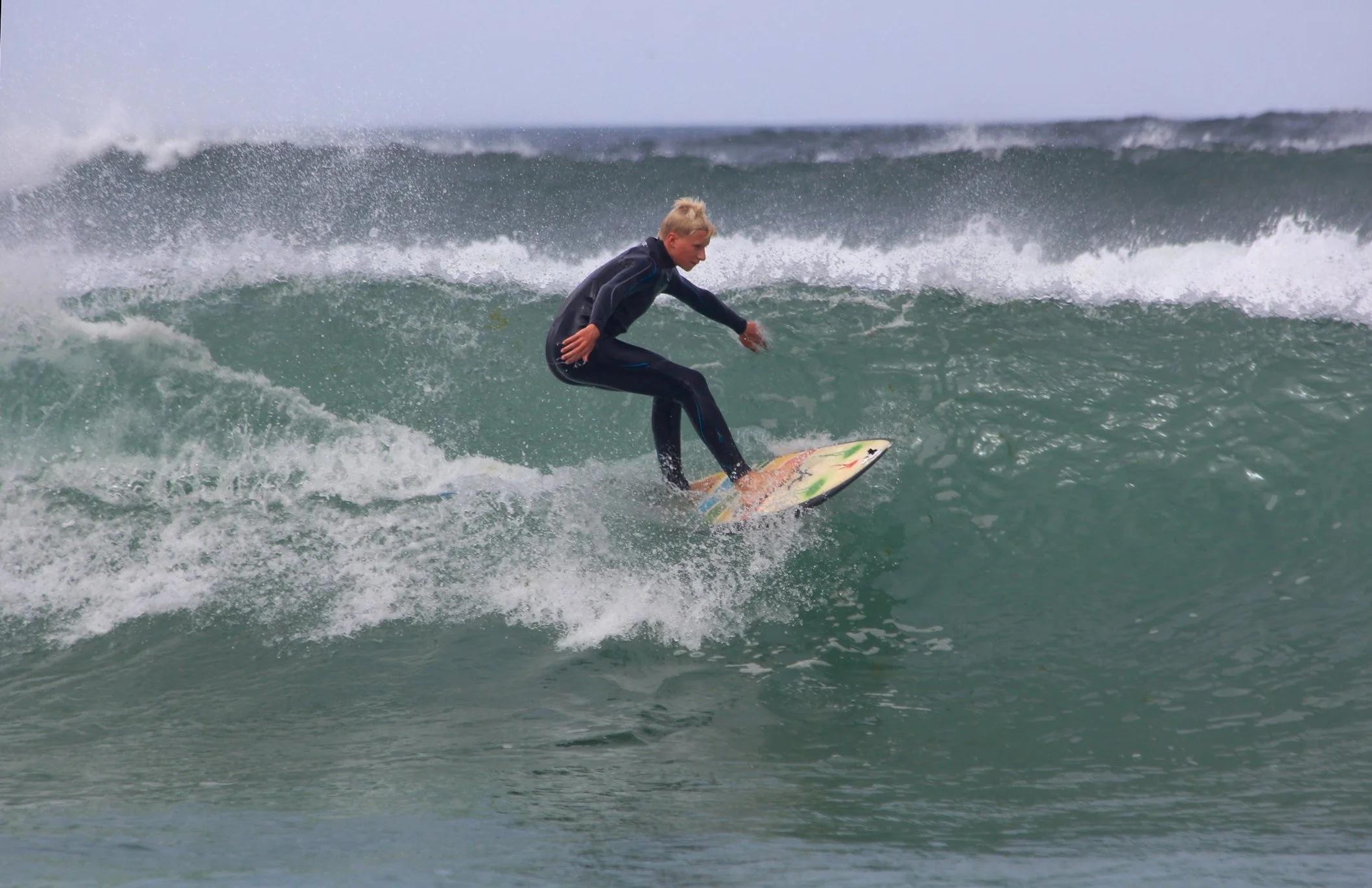 Person surfing on a wave in the ocean during daytime.