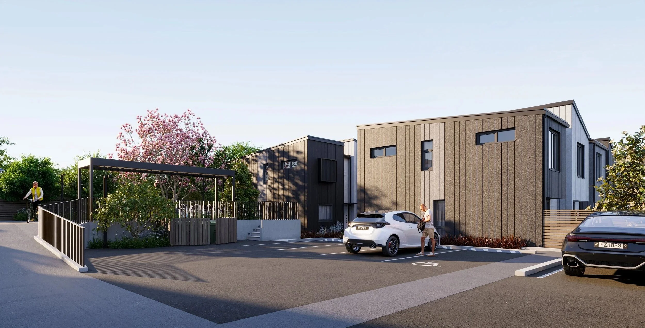Northgate Estate, New Plymouth apartment complex with parking lot, a white electric car, a person standing beside it, a person riding a bicycle on the left, and landscaped greenery including a blossoming tree.