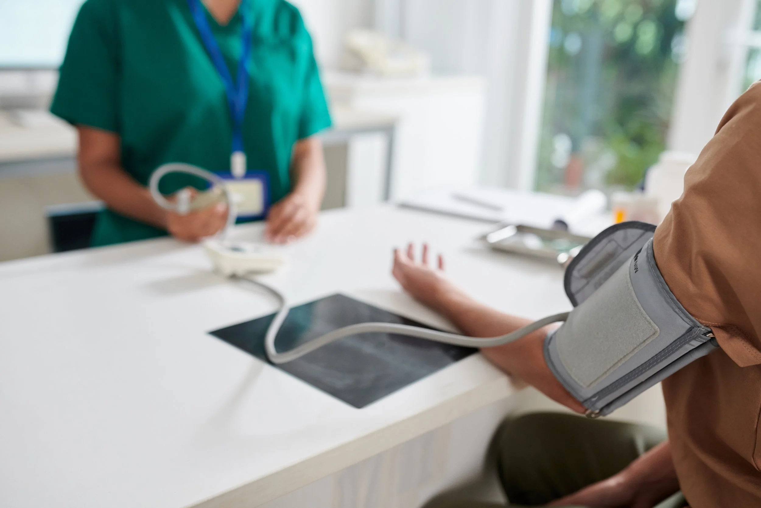 A person having their blood pressure taken by a healthcare professional in a clinic setting.