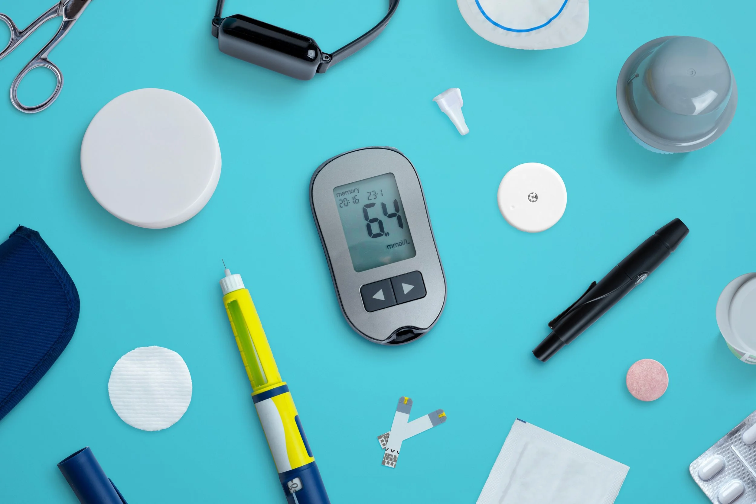 A collection of medical items including a glucose meter showing 6.4, a blood sample lancet, an insulin pen, pills, medical tape, a black pen, a sticky note pad, a packet of medication, and other health-related supplies on a blue background.