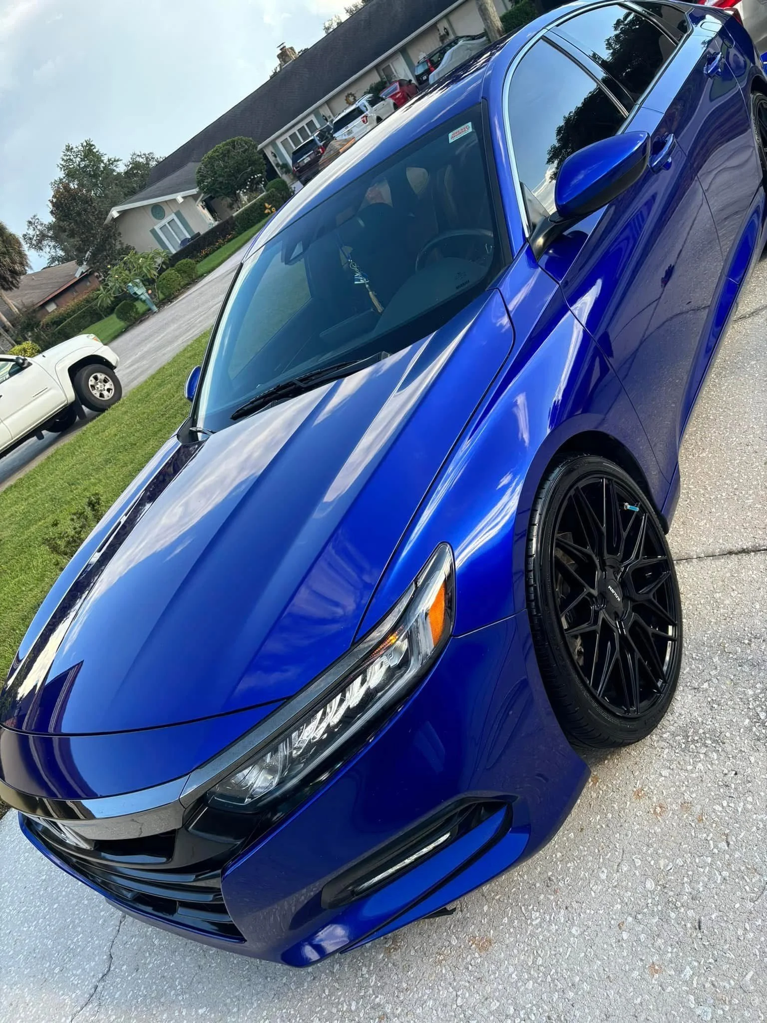 Blue sports car parked on a driveway in a residential neighborhood.