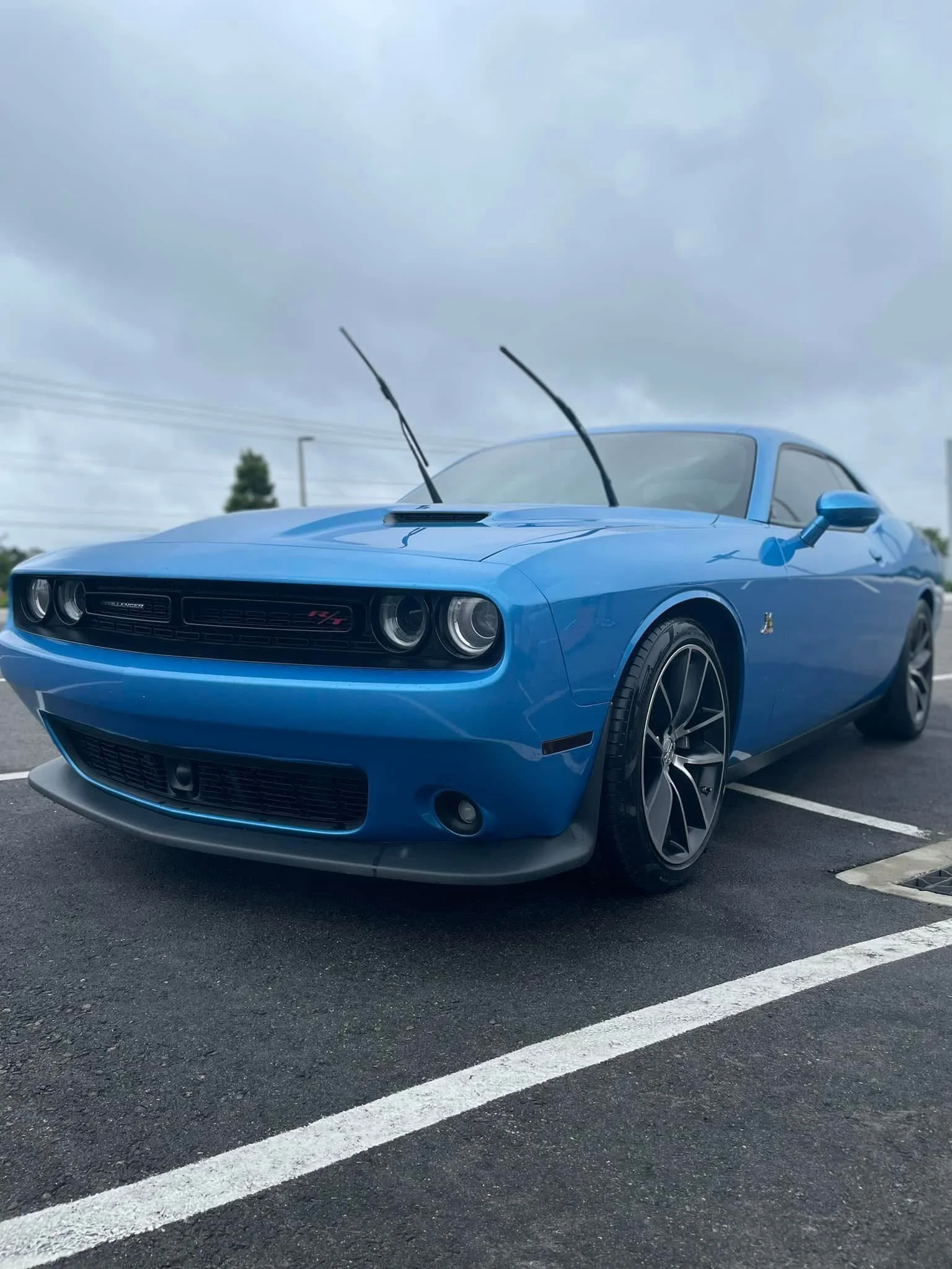 Blue Dodge Challenger R/T parked in a parking lot under cloudy skies.