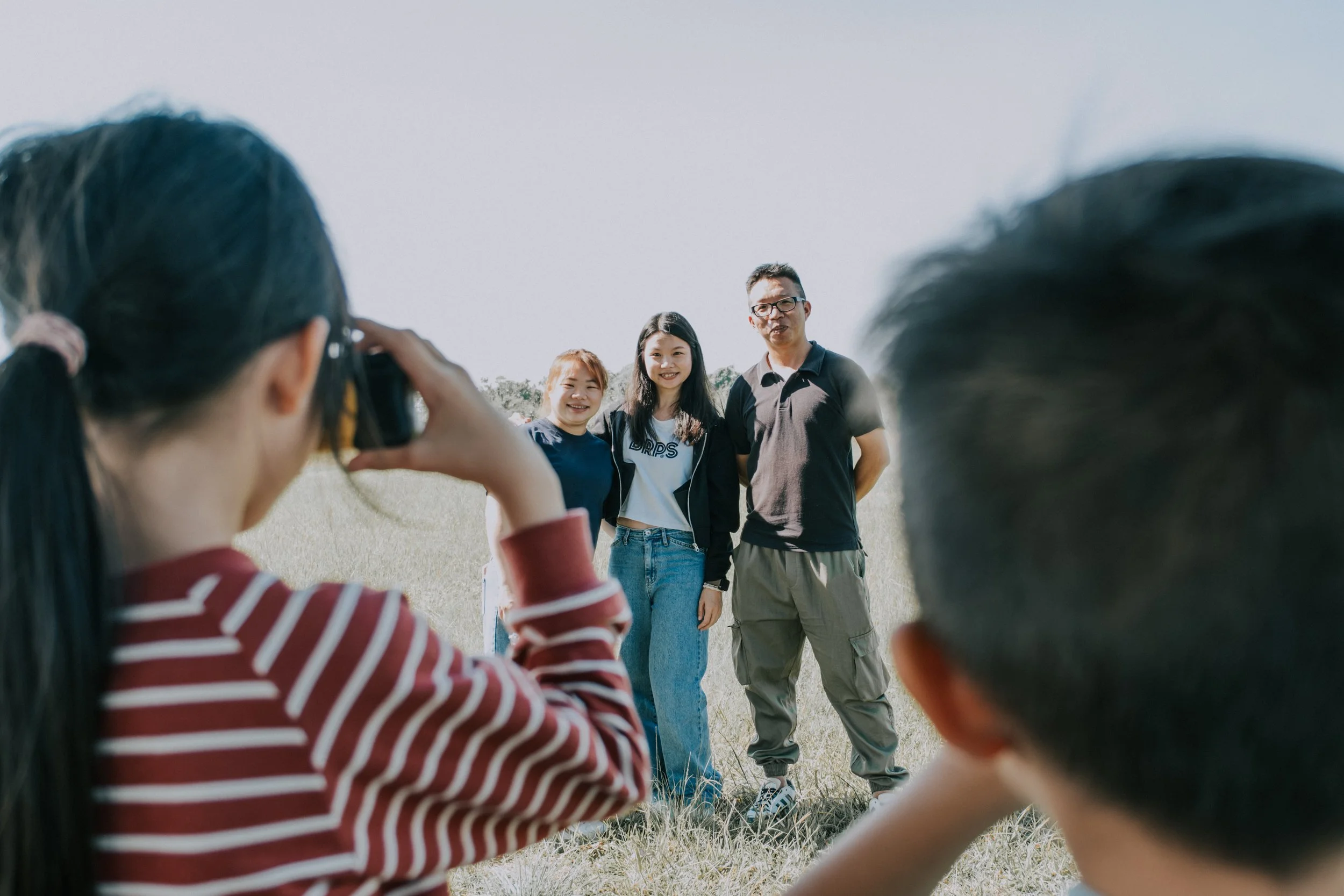 台中大家庭戶外寫真｜全家人站在草地上的背影，自然光下溫暖的家族紀念攝影