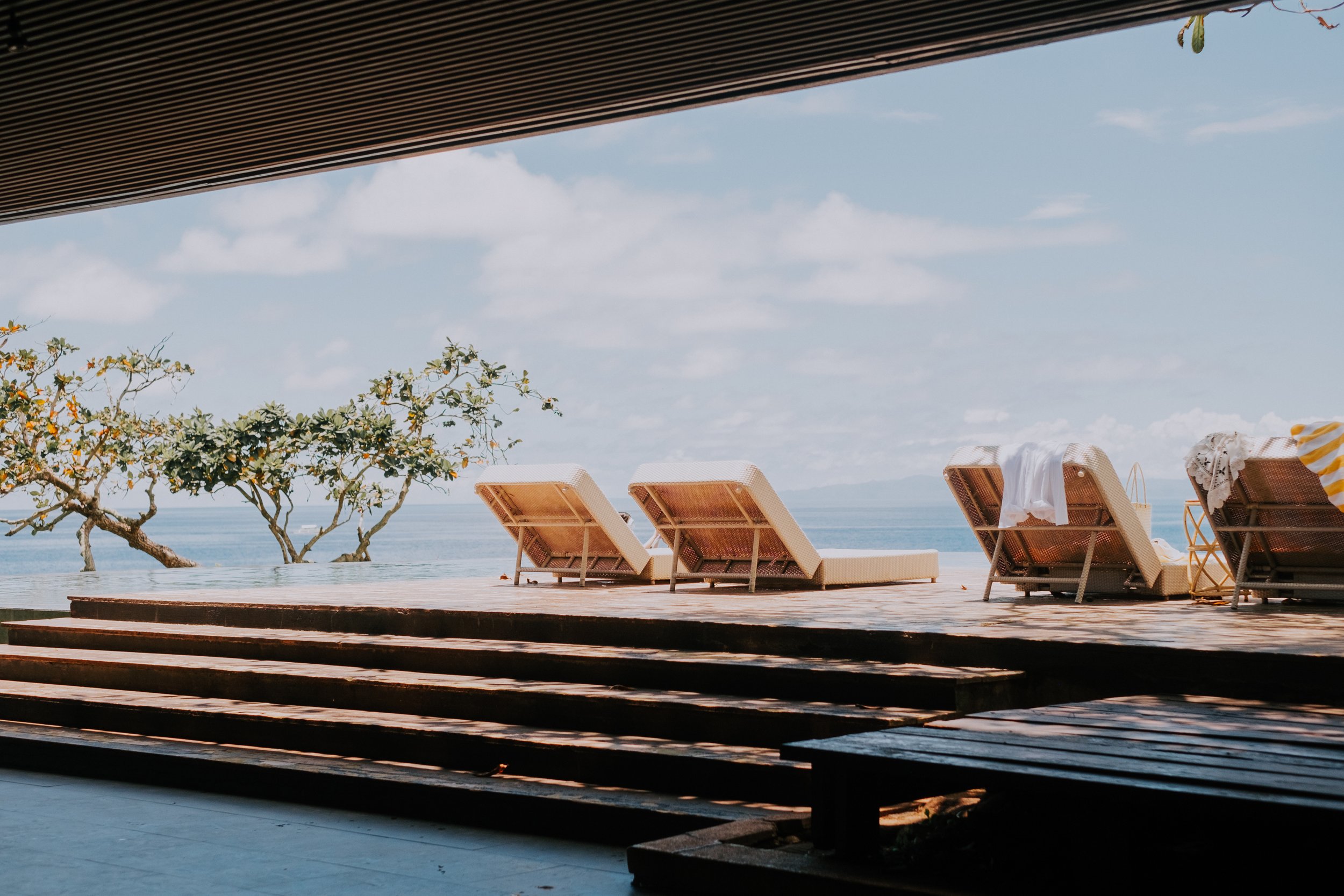 商業攝影｜熱帶度假別墅泳池露台，木質躺椅與海天景觀空間攝影