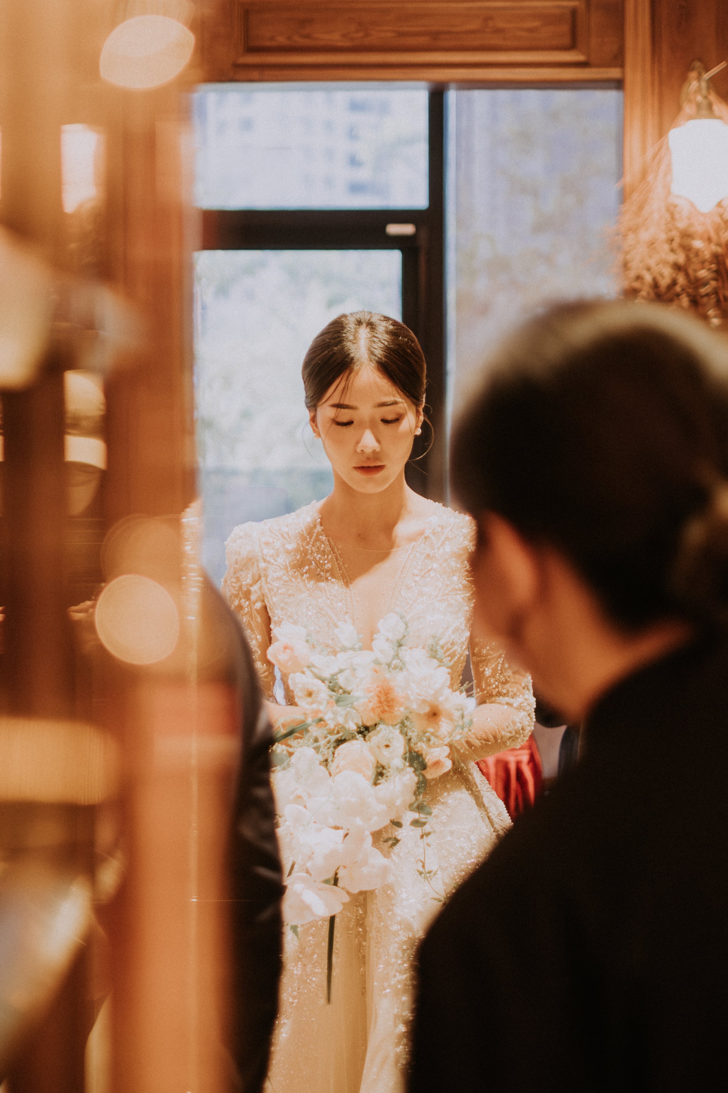 台灣婚禮攝影｜新娘手捧花束站在暖色光線下，準備走向另一半的溫柔時刻