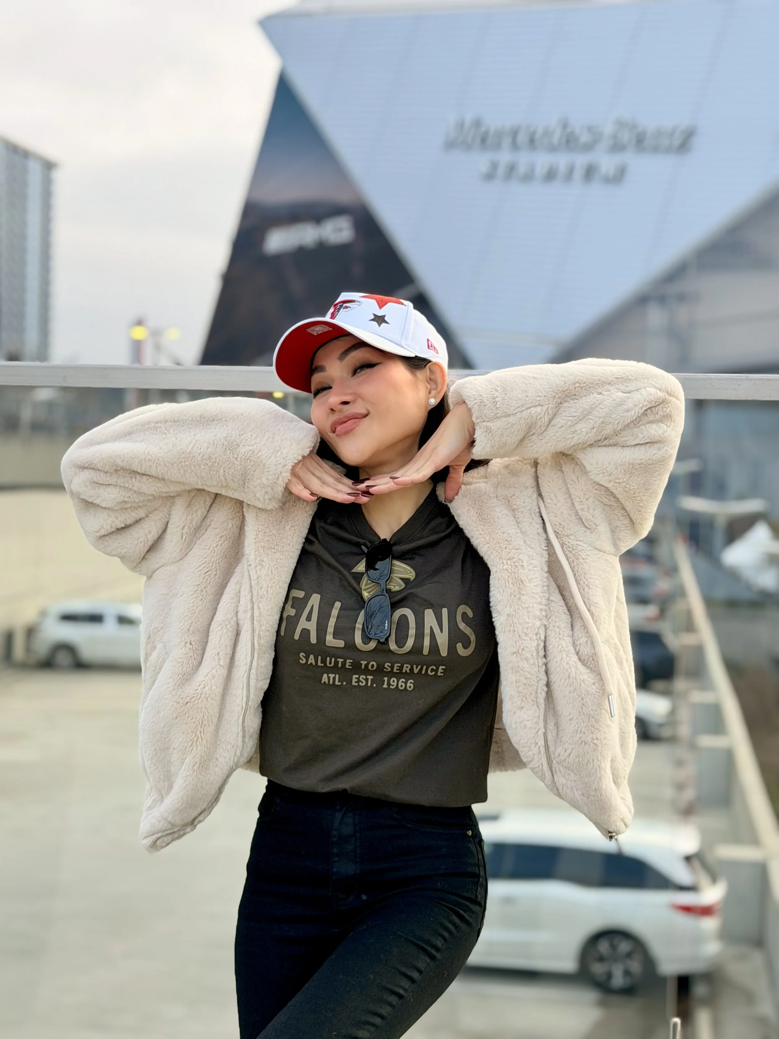 Trang T. Nguyen in Falcons gear posing outside Mercedes-Benz Stadium with hands under her chin.