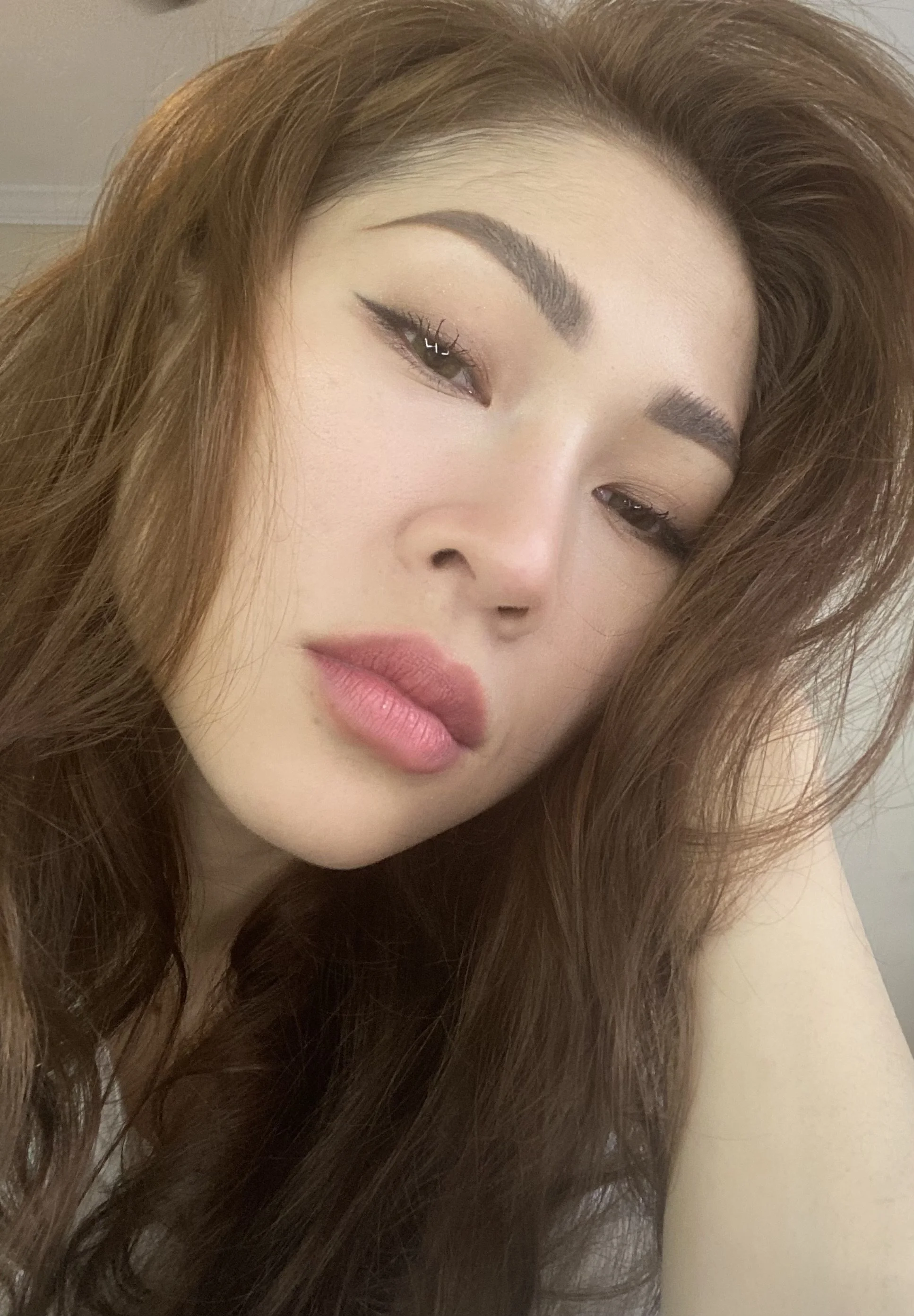 Close-up beauty portrait of Trang T. Nguyen with soft glam makeup and long hair, neutral background.