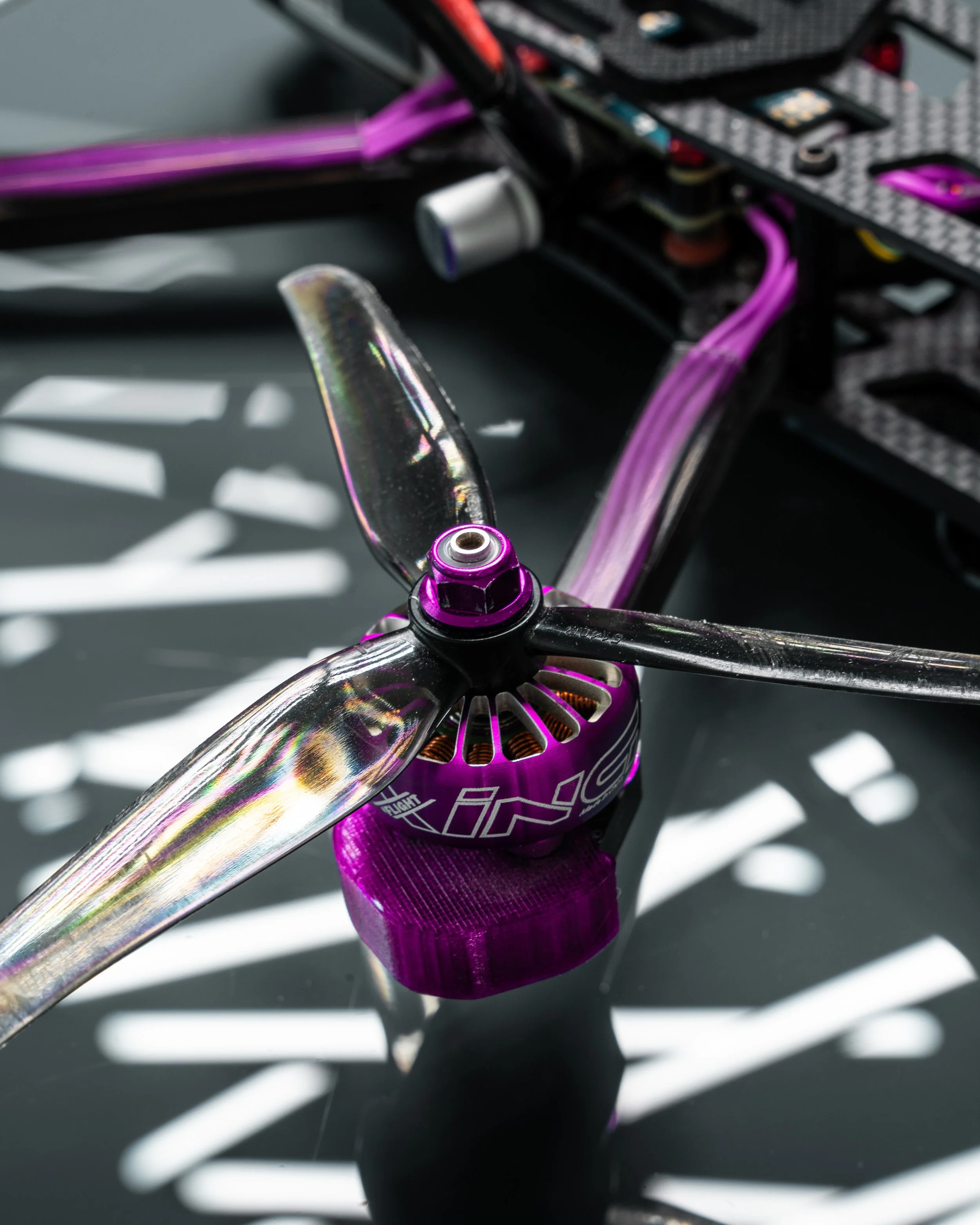 Close up of a 5" FPV Freestyle drone motor and propeller with the drone components in the background