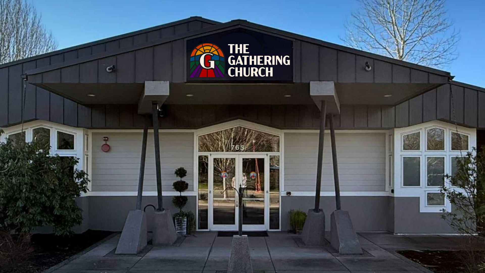 Exterior of The Gathering Church building with large signboard displaying the church's name and logo, glass entrance doors, and landscaping