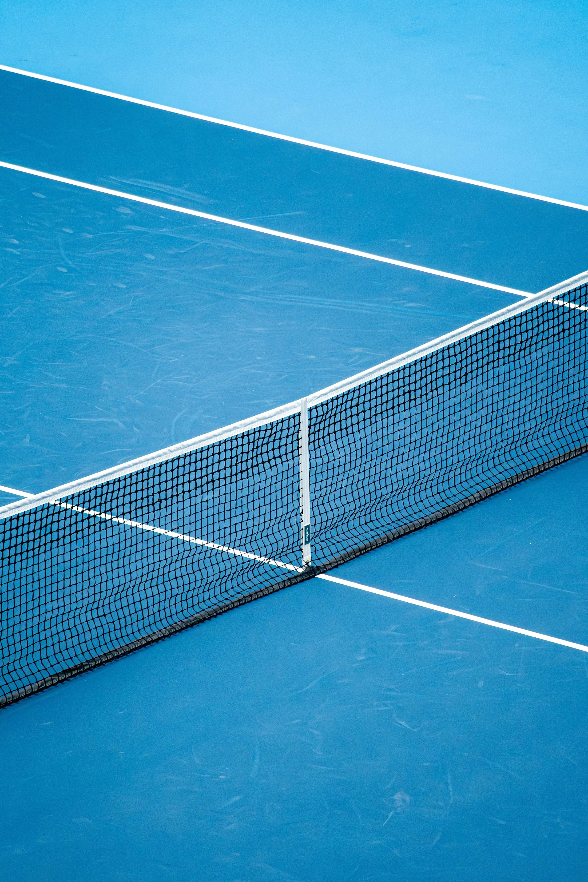 A close-up view of a blue tennis court with the net in focus.