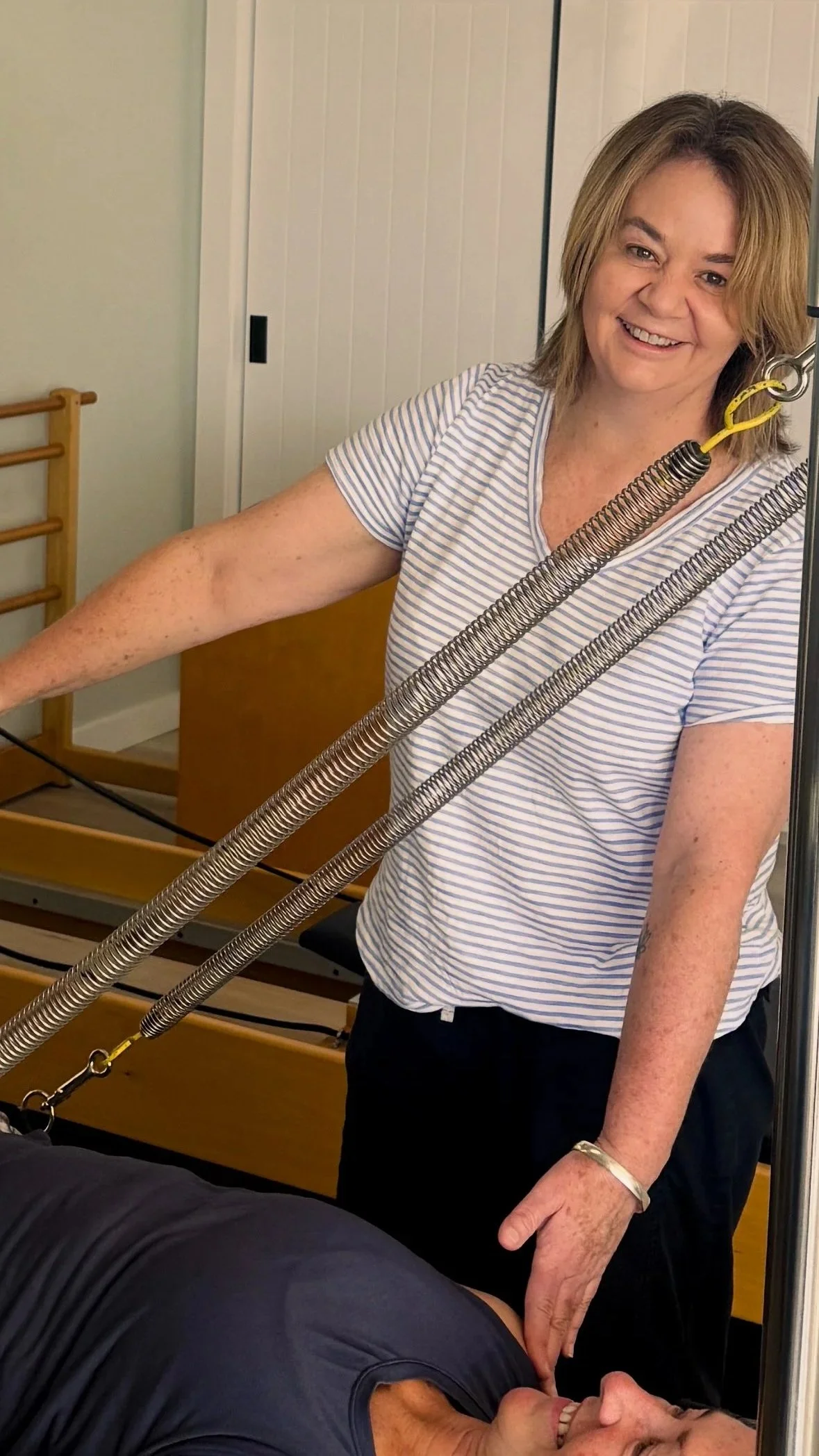 The owner of Intune Life studio in Ulladulla smiling while supporting a pilates client during a class