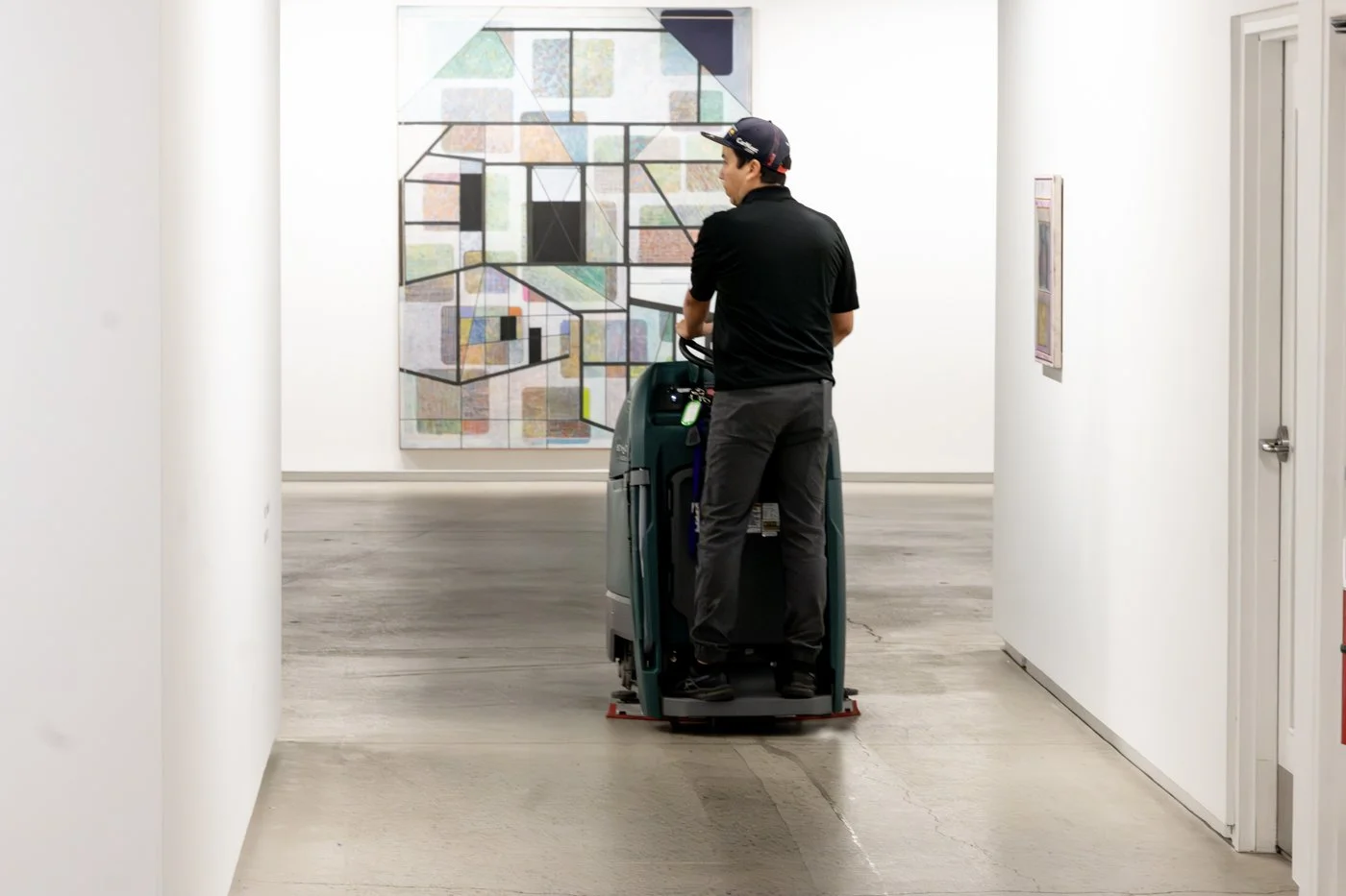 A person operating a floor cleaning machine in an art gallery or museum.