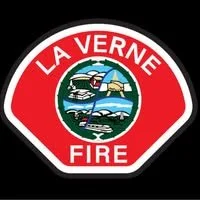 La Verne Fire Department emblem with a red background, featuring a scene of a boat, a lighthouse, and hills.
