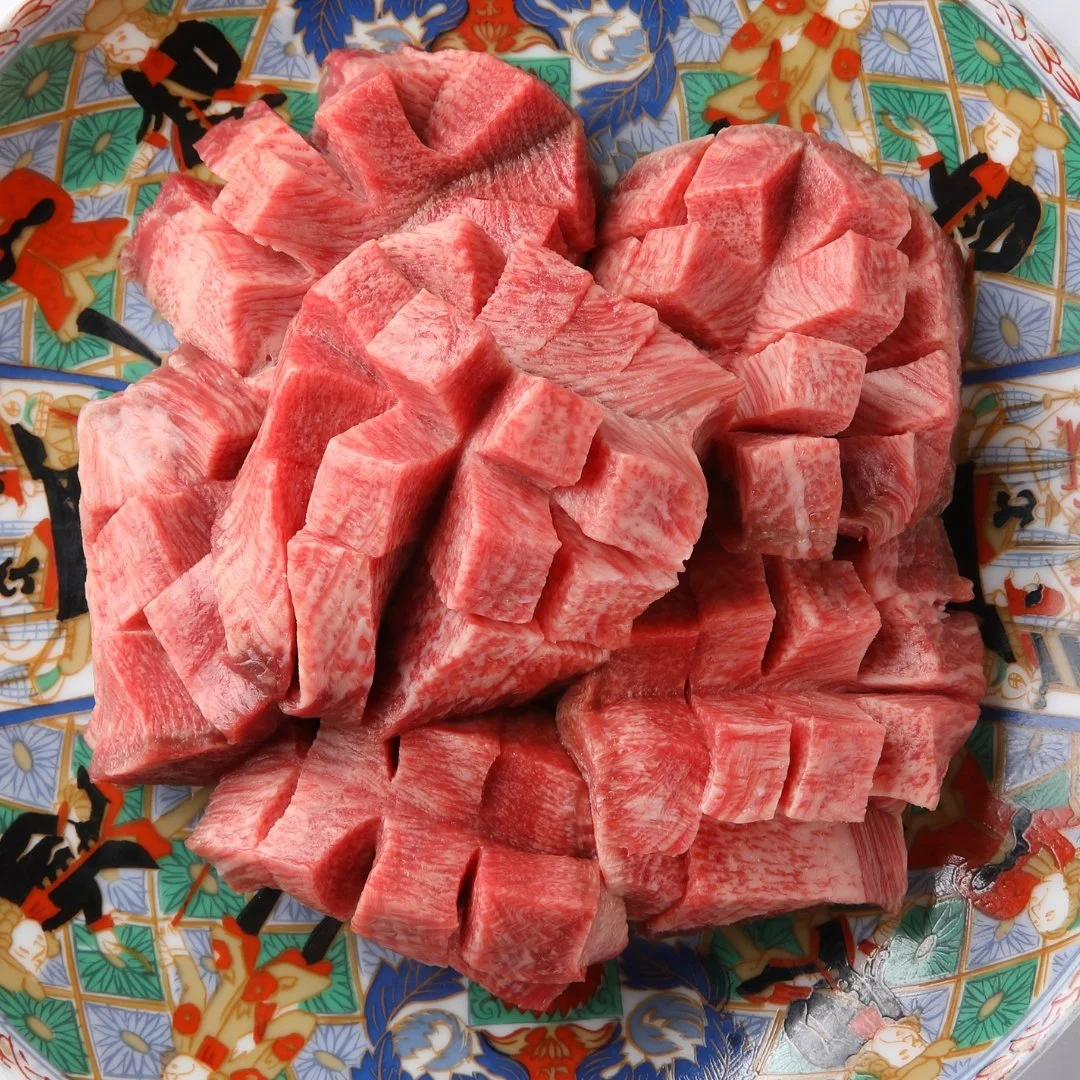 高級和牛のサク。細かく切り分けられた薄い肉の塊が、華やかな伝統的な模様の皿に載っている。