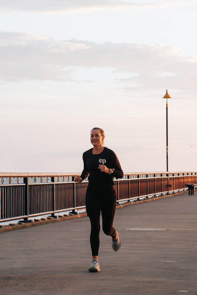 Woman jogging on a pier during sunset