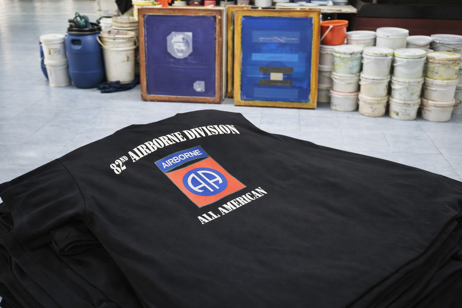 Multiple rubber printing tables aligned for efficient bulk screen printing in a garment factory.