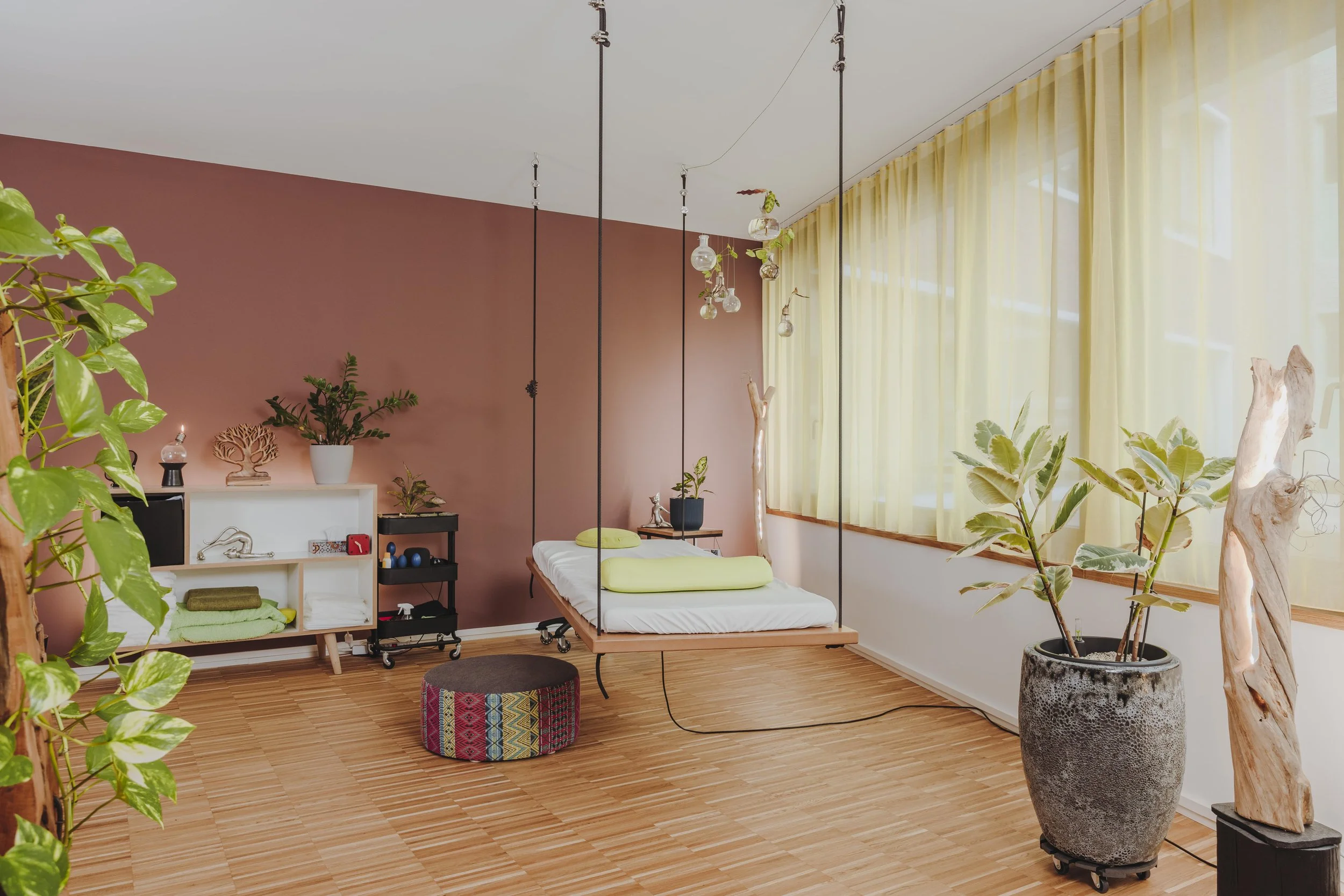 Ein Raum mit einem schwebenden Bett, umgeben von Pflanzen und natürlichem Licht, in warmen Farben gestaltet.