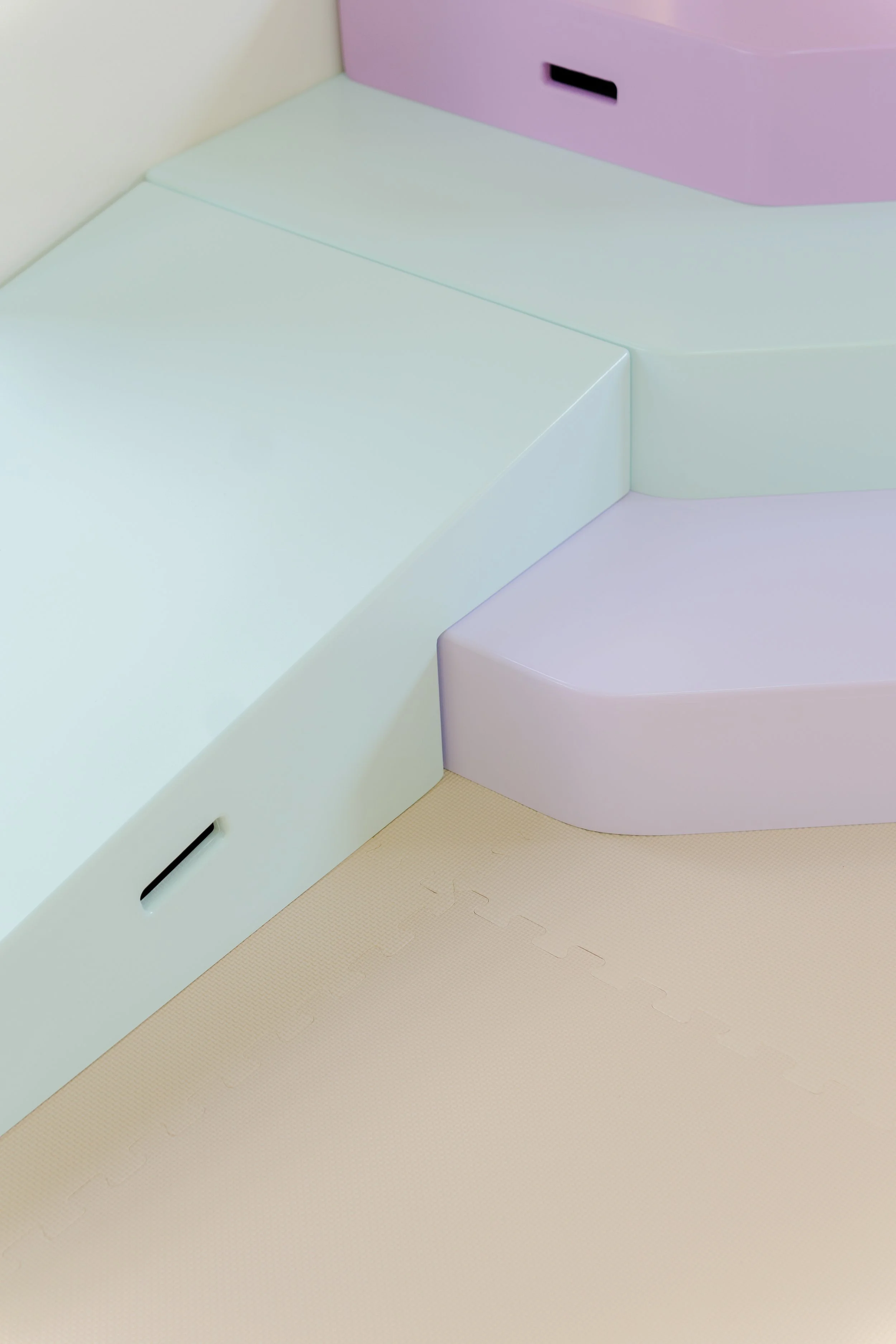 Superficie de color pastel, con formas geométricas suaves y esquinas redondeadas, en colores azul, rosa y beige.