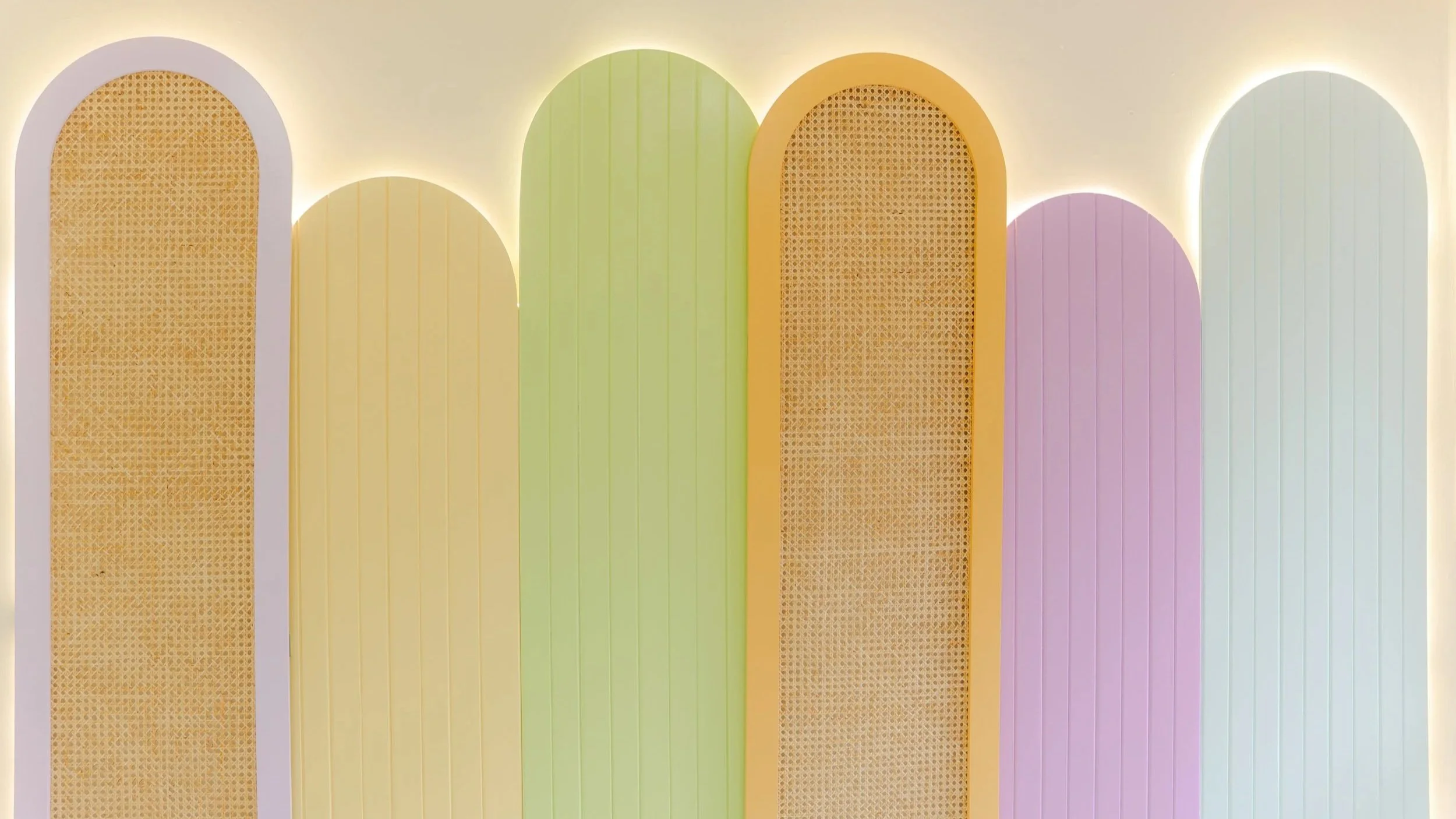 Conjunto de paneles decorativos en colores pastel con iluminación detrás, en tonos amarillo, verde, naranja, rosa y azul claro.