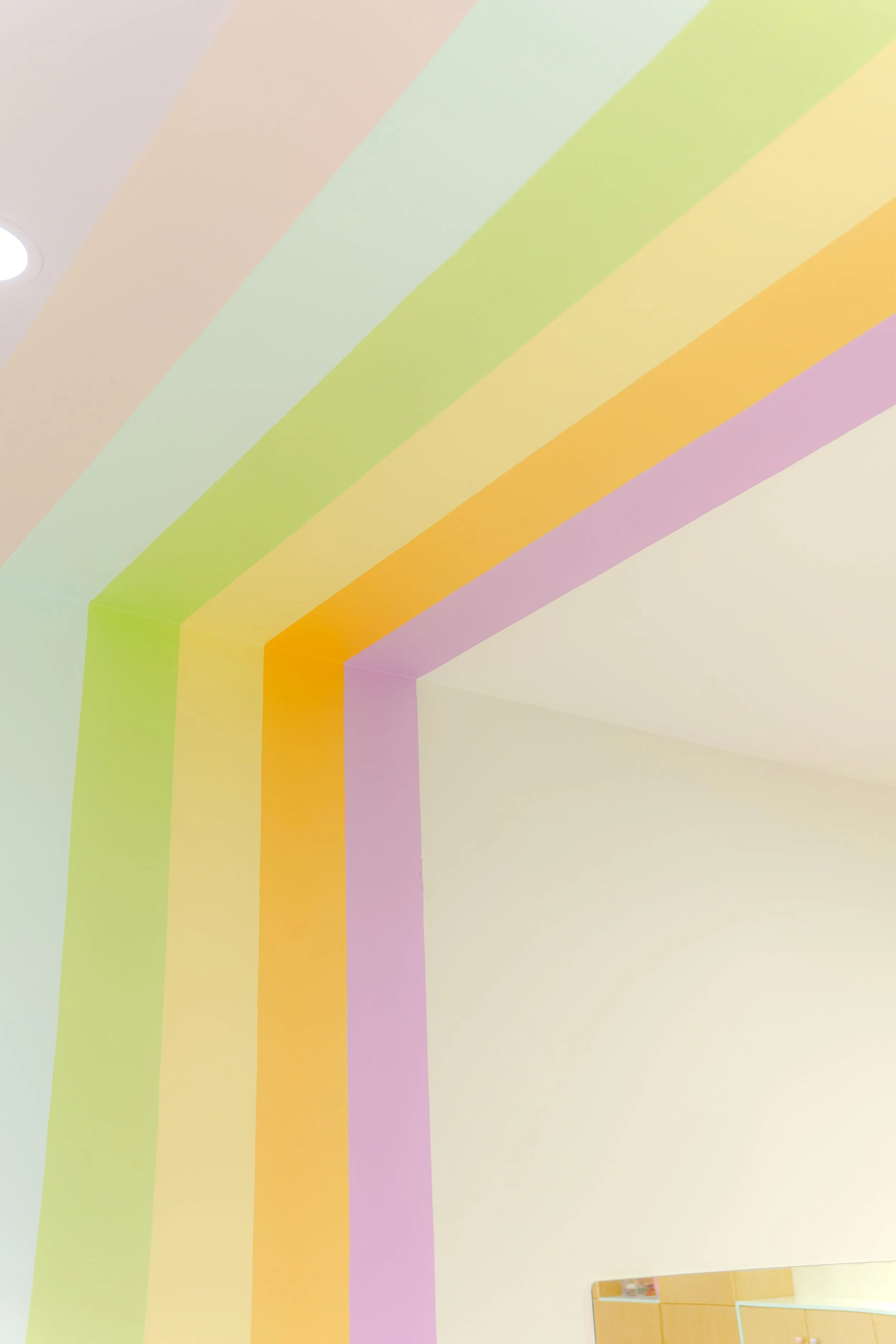 Sala con paredes pintadas con arcoíris en colores pastel y silueta de espejo en la esquina inferior derecha