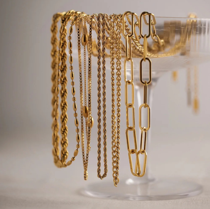 Gold jewellery draped over cocktail glass
