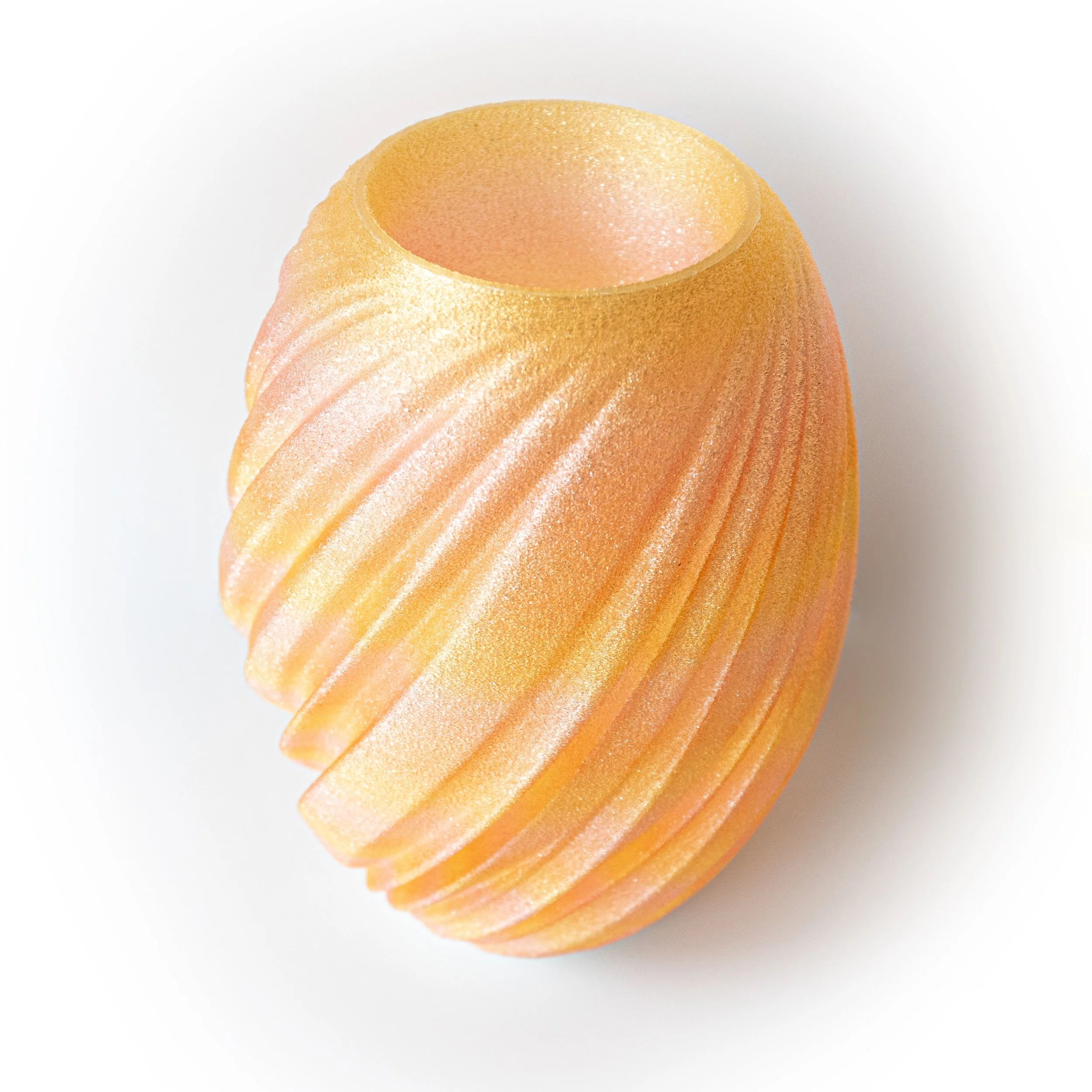 An oval yellow 3d printed lamp with a textured surface, sitting on a white canvas