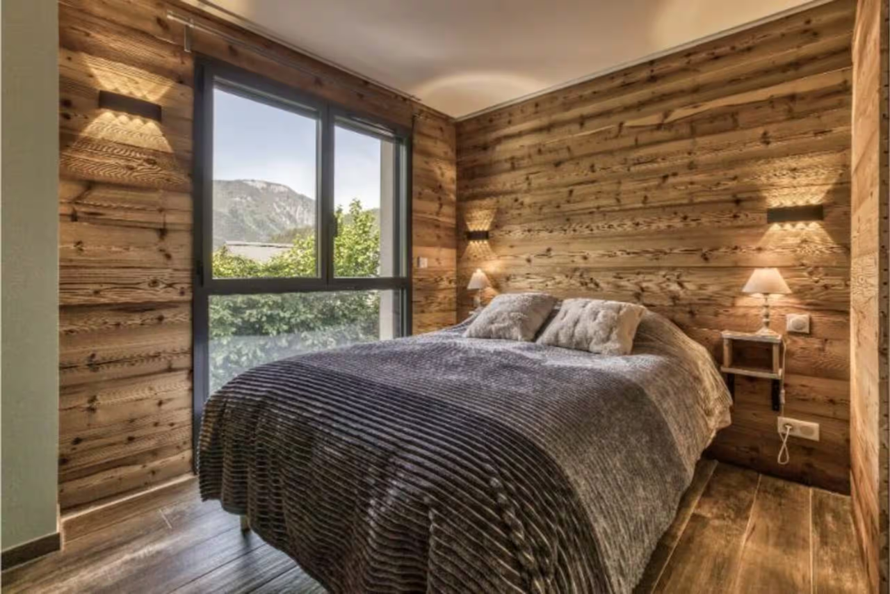 Double bedroom with timber walls and mountain views