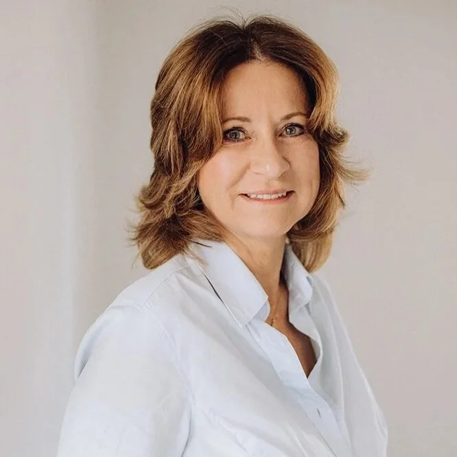 Ein Portrait Bild von Carola Brinkers sie schaut freundlich in die Kamera hat braune Schulterlange Haare und trägt eine helle Bluse.