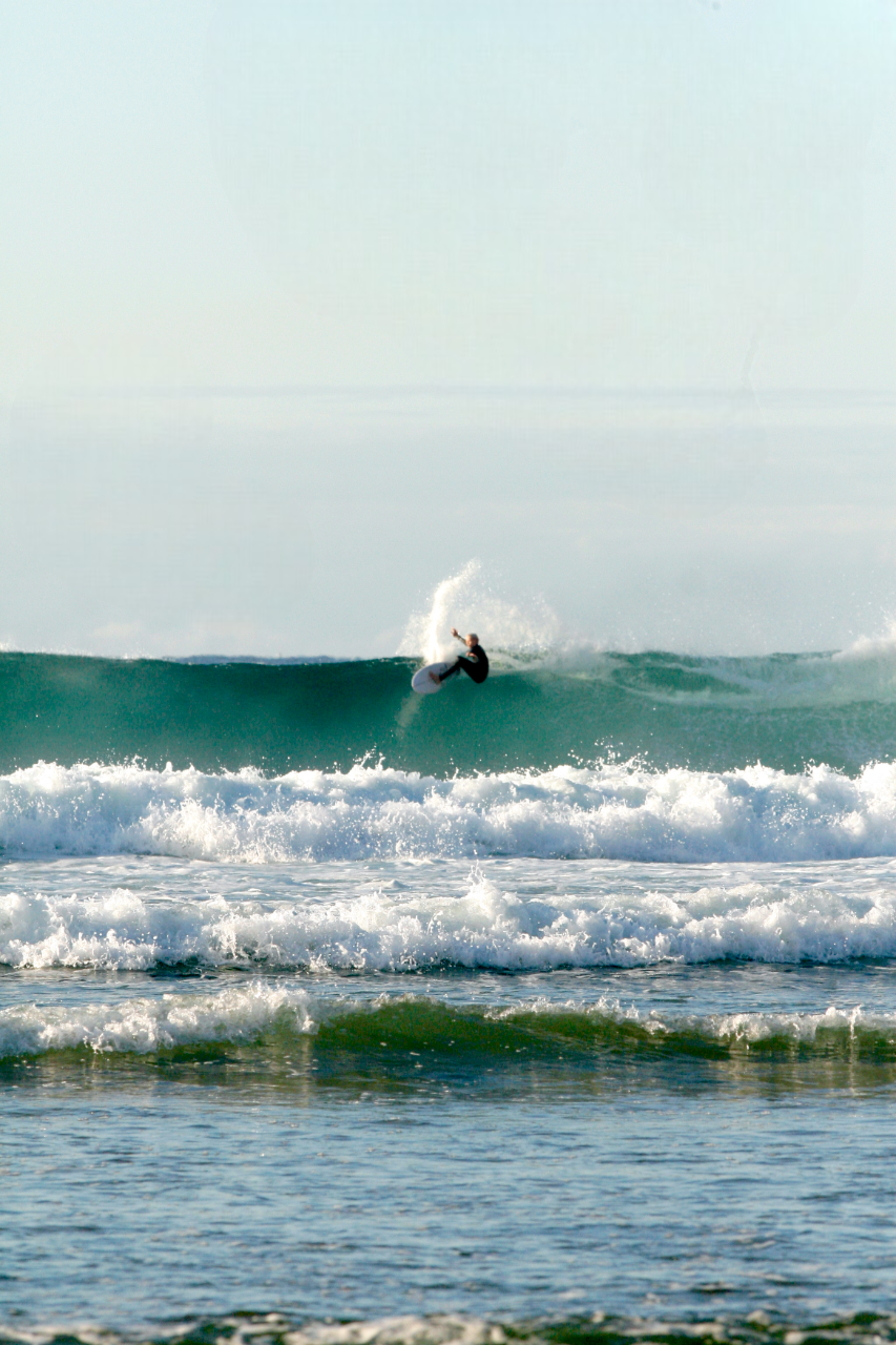 A person surfing on a wave in the ocean on a clear day.