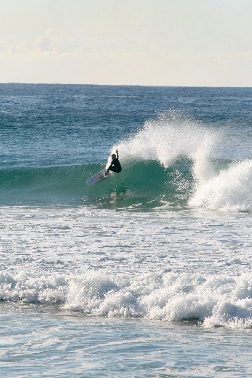 A person surfing on a wave in the ocean during daytime.