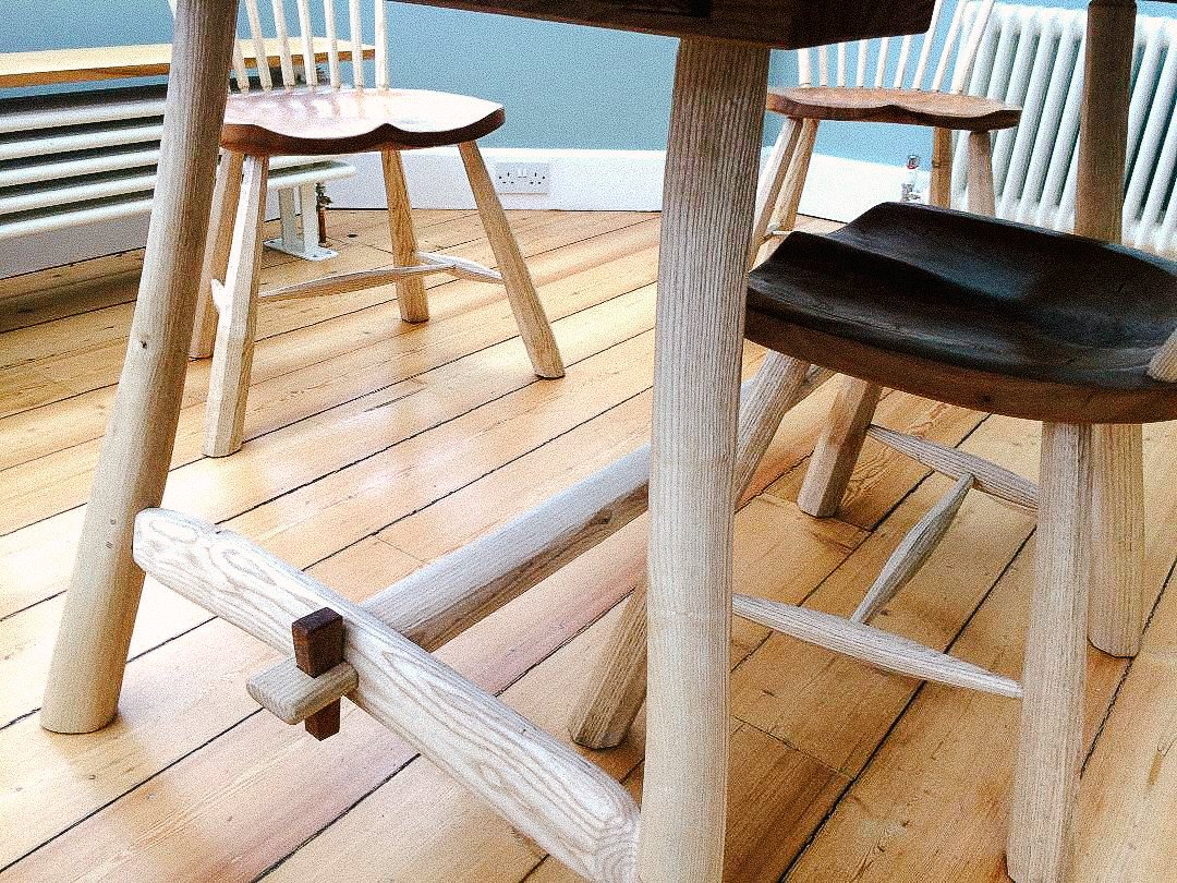 Wooden furniture including chairs and a table on a wooden floor inside a room.