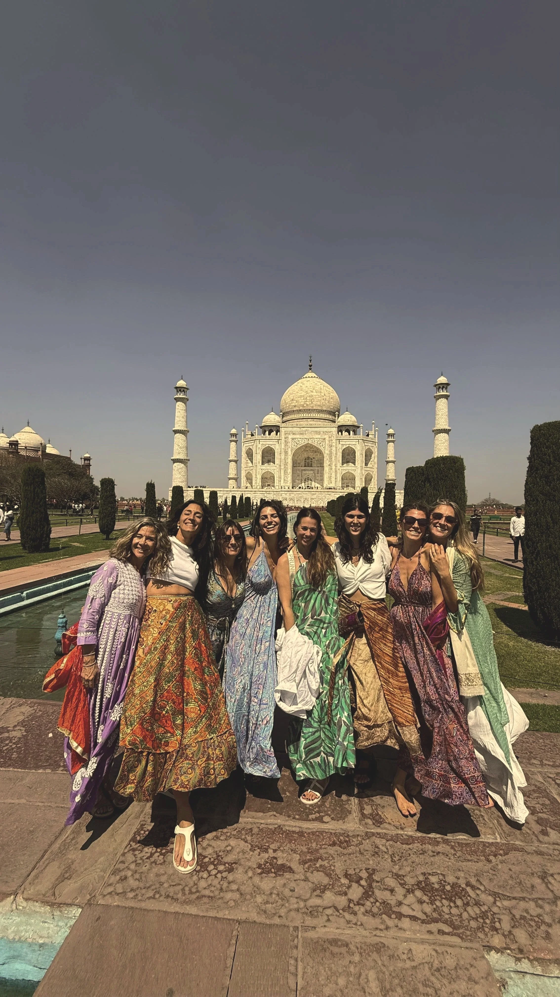Grupo de mujeres posando frente a la columnata y la fachada principal de la Torre Taj Mahal en India.