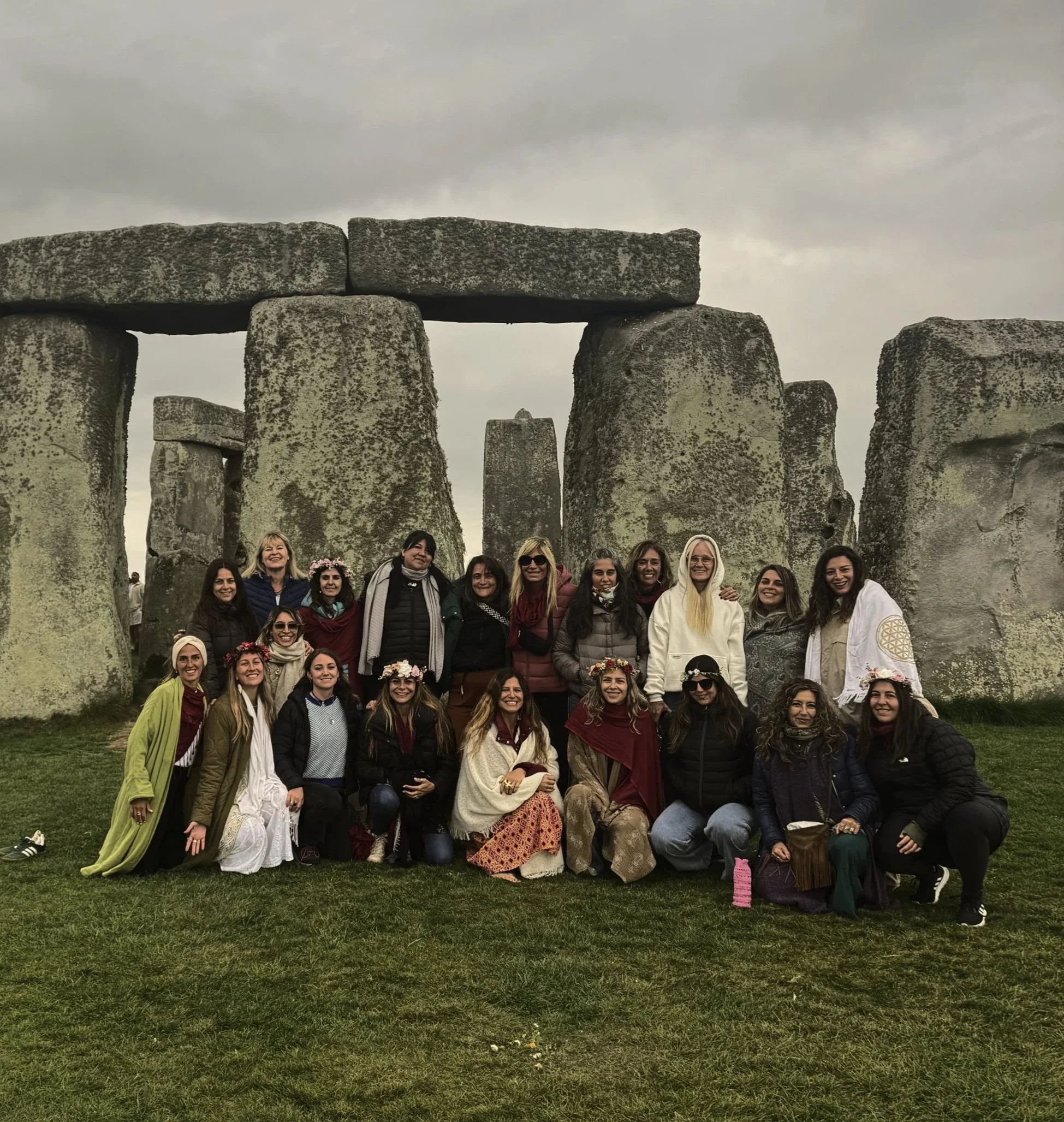 Un grupo de personas posando frente a Stonehenge en un día nublado.
