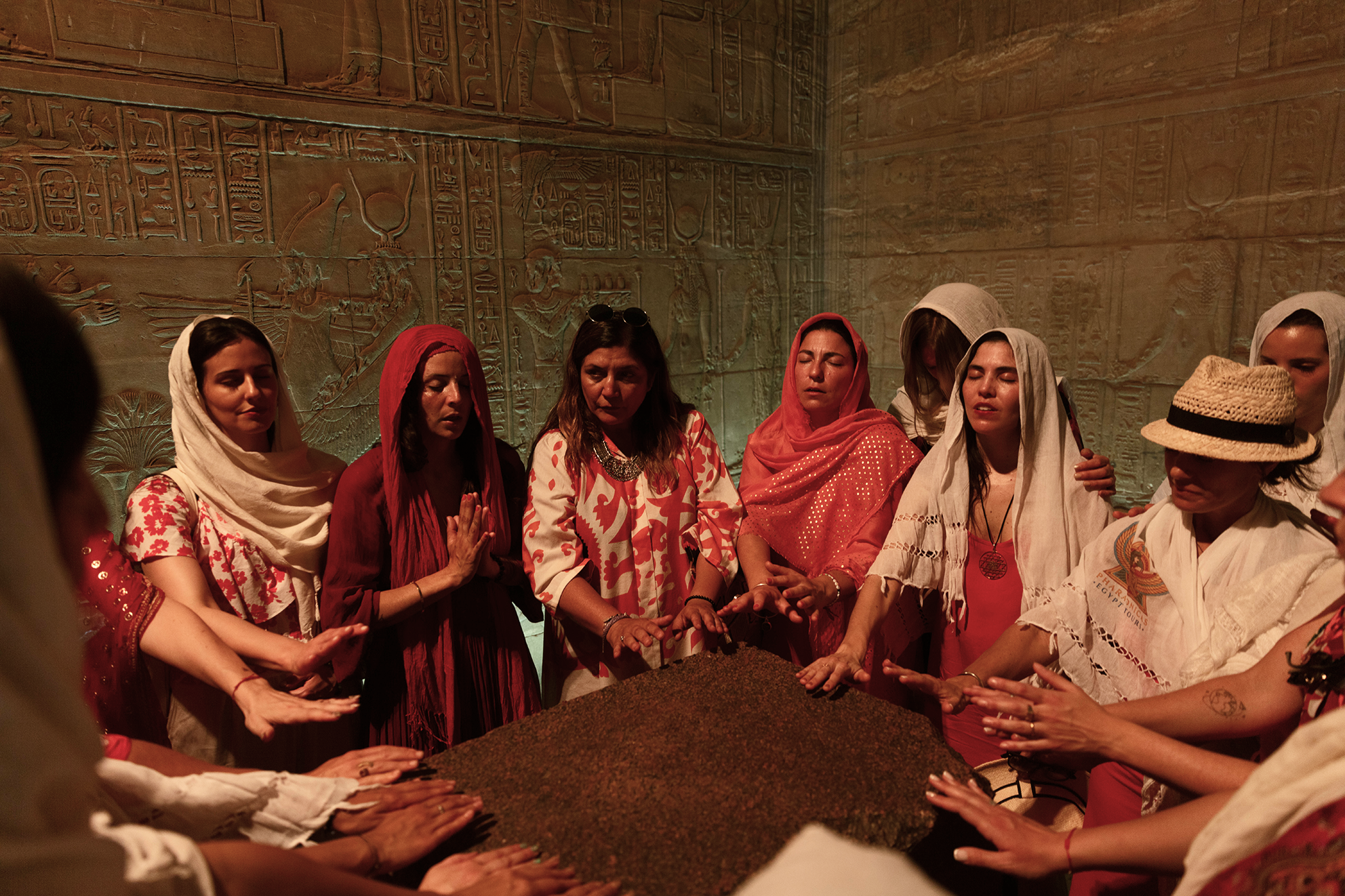Grupo de mujeres con ropa tradicional en un ritual en un museo de antigüedades con paredes con jeroglíficos egipcios.