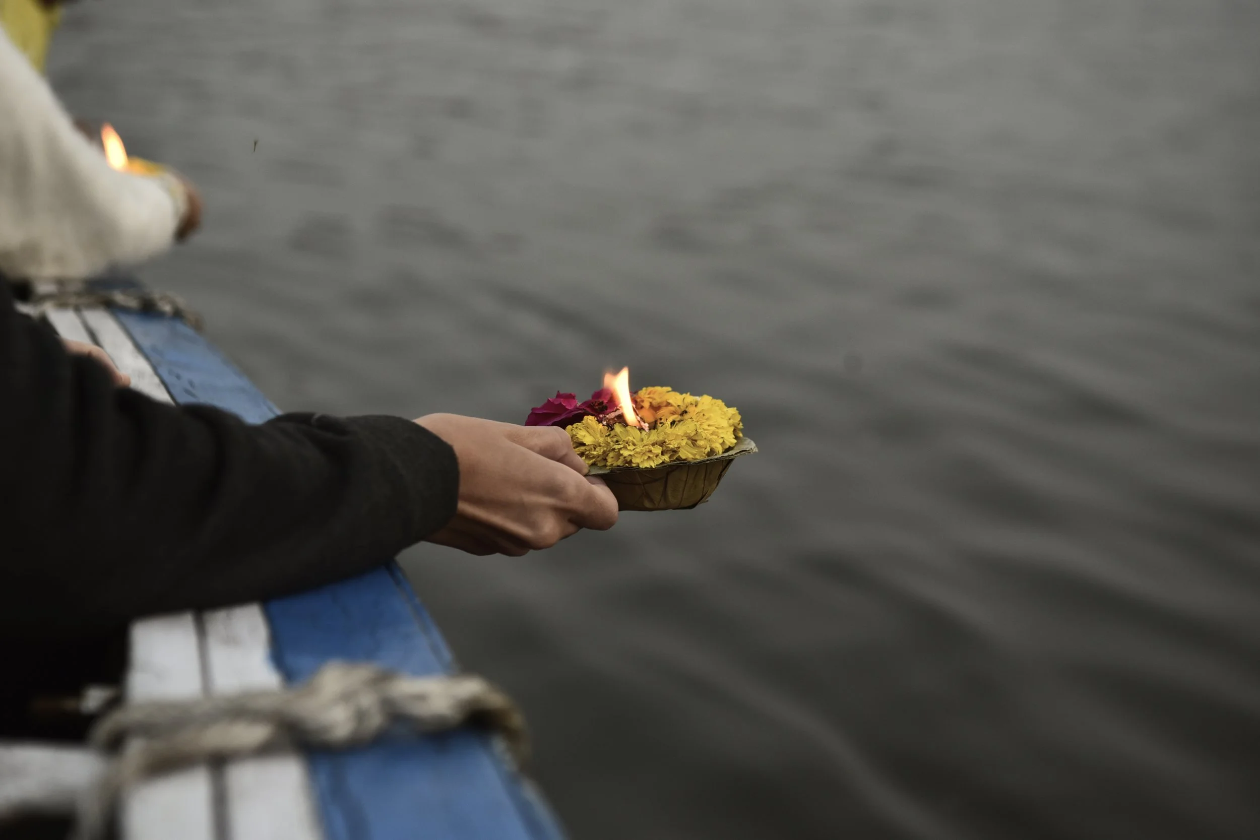 Una persona sosteniendo una lámpara de flores (entra en llamas), con un cuerpo de agua al fondo.