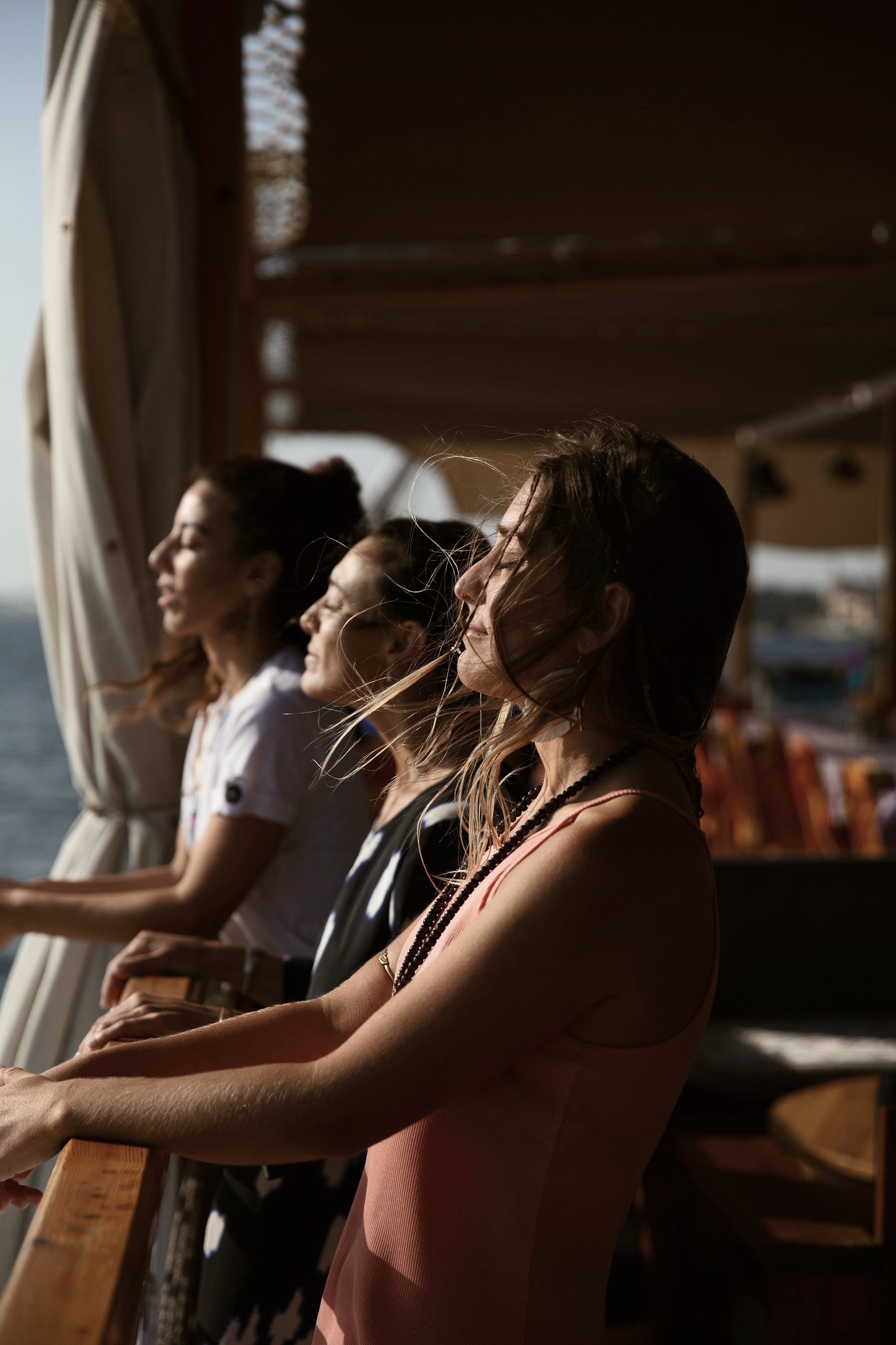 Cuatro mujeres mirando hacia adelante en un barco, con viento en el cabello, disfrutando del atardecer.