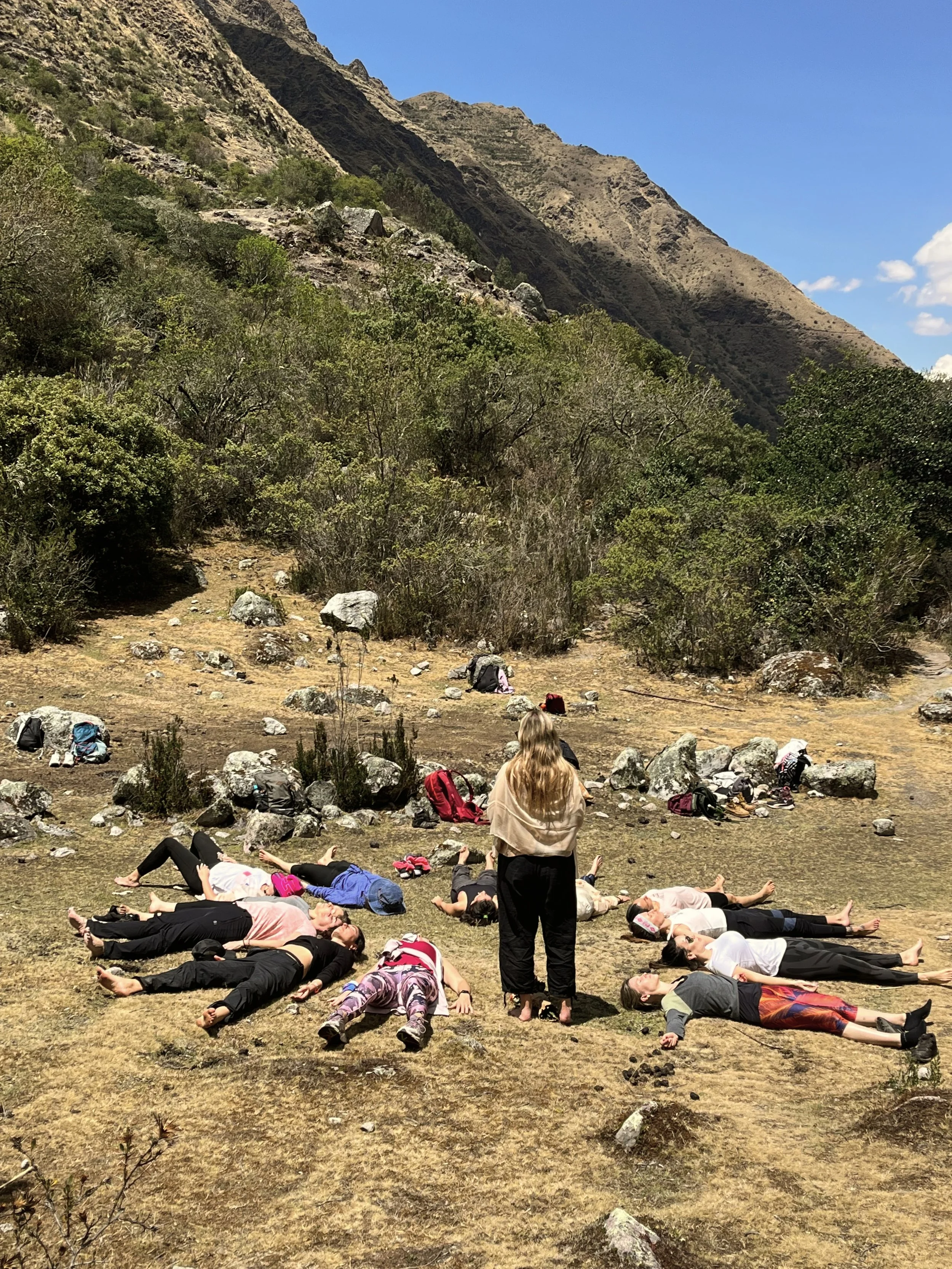 Grupo de personas tomando una siesta en un campo en un paisaje montañoso y despejado.