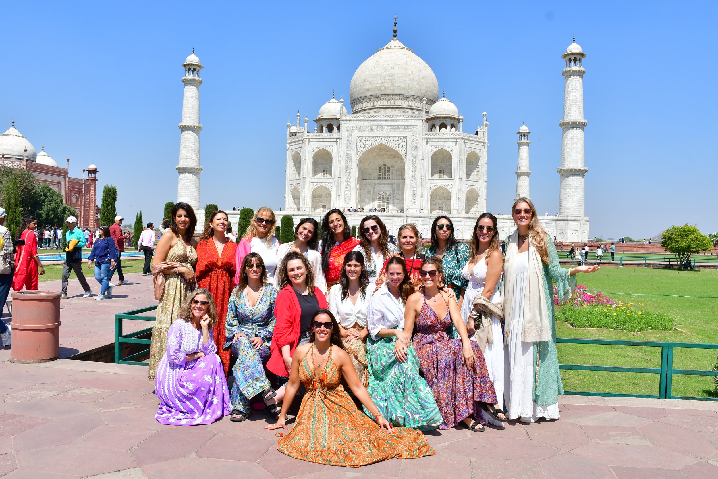 Grupo de mujeres posando frente la Taj Mahal en India, en un día soleado